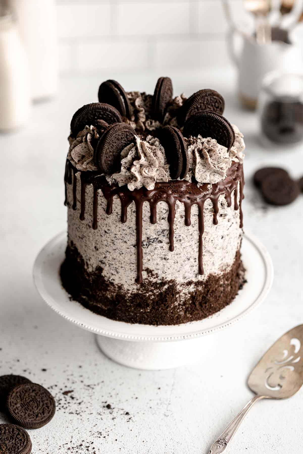 gluten free oreo cake on a cake stand with chocolate drips