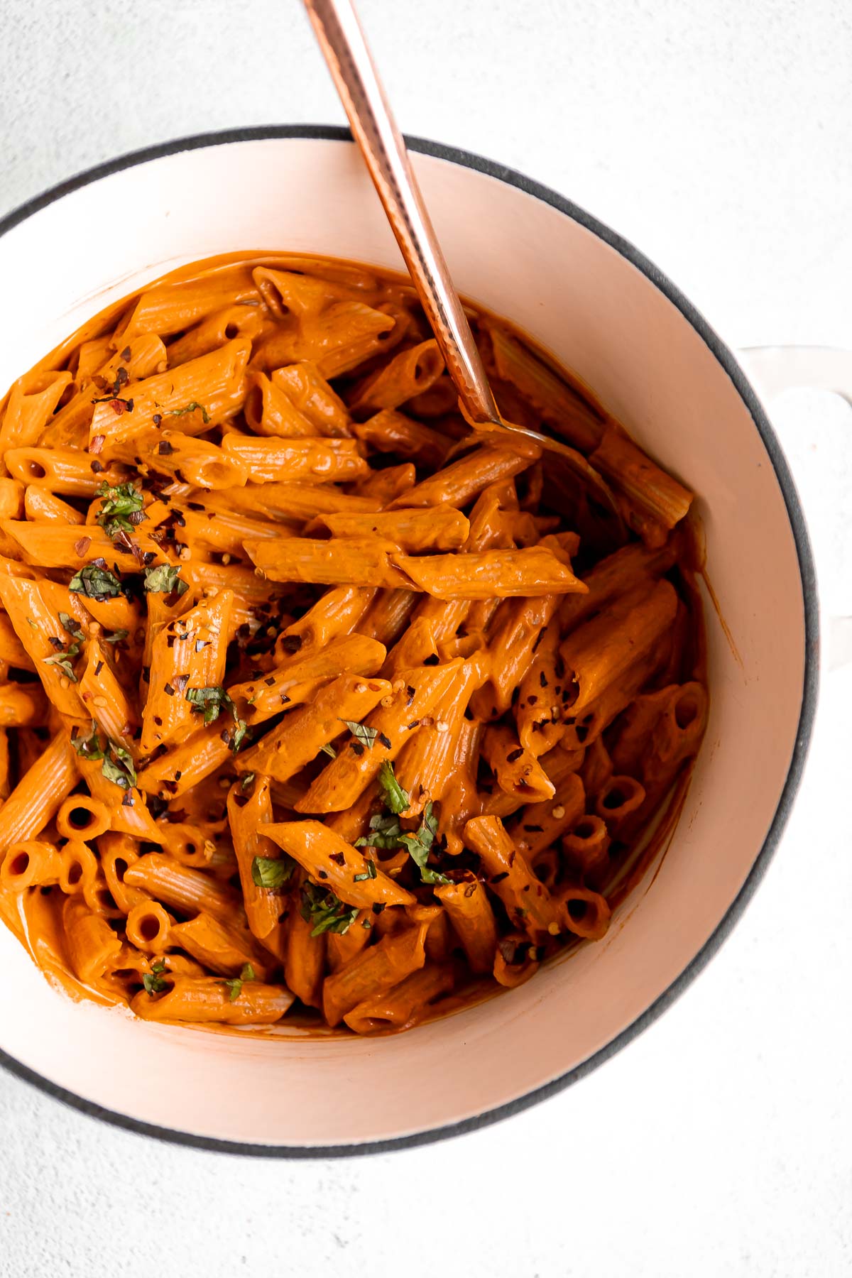 spicy vodka pasta in a large pot with basil on top