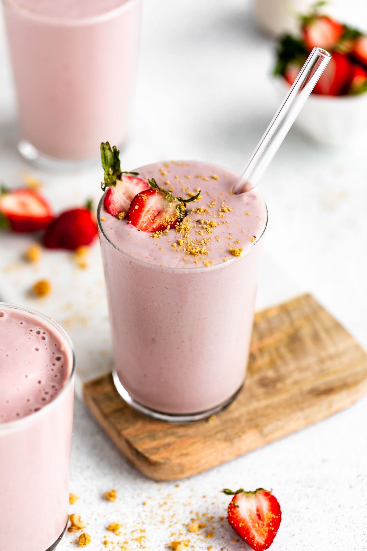 three glasses with the banana protein shake with sliced strawberries