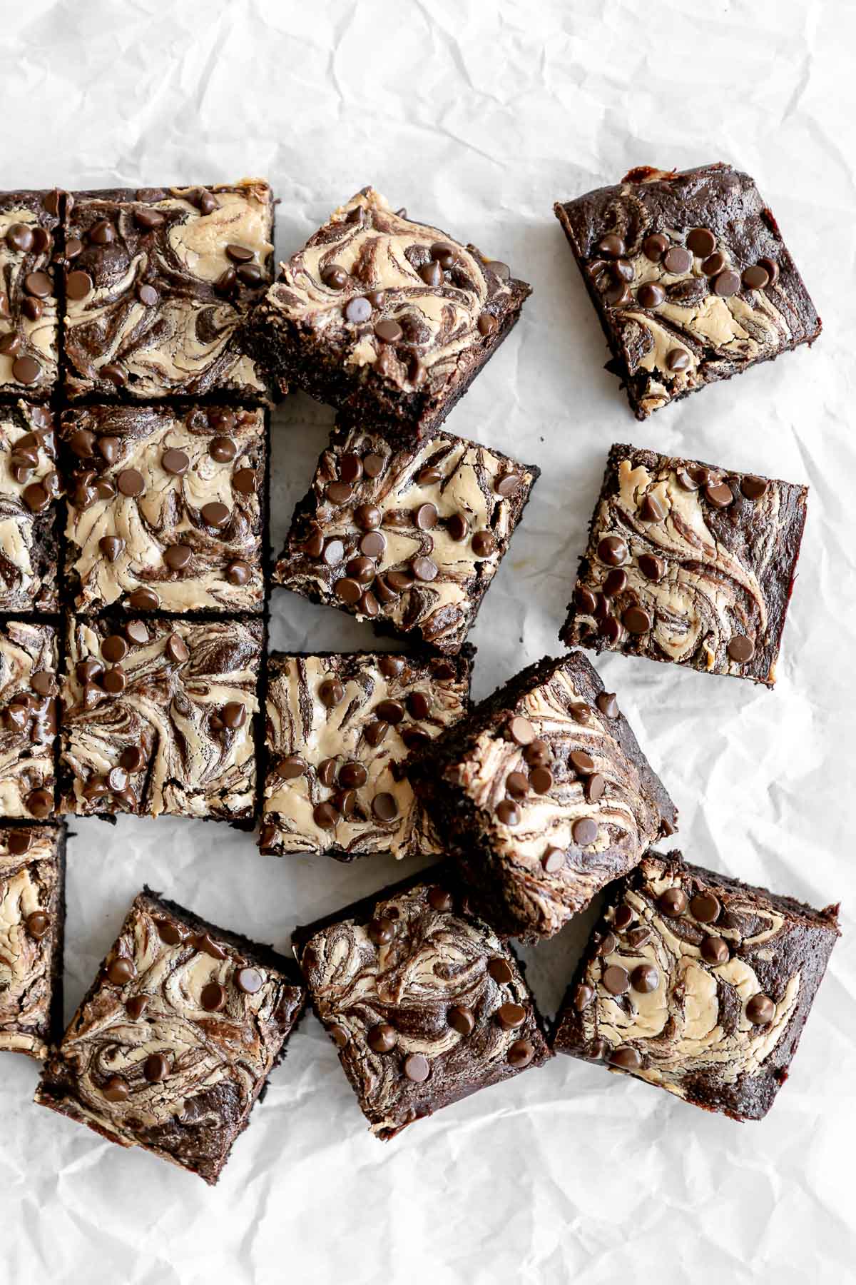 tahini brownies on parchment paper sliced into squares with chocolate chips