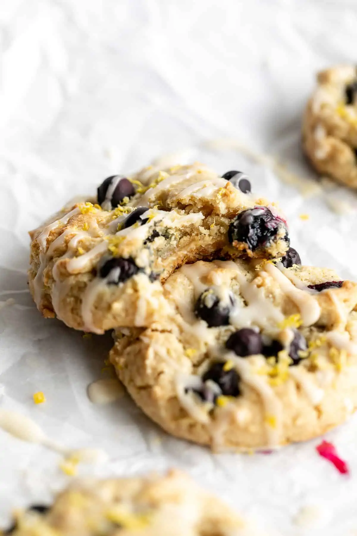 vegan lemon blueberry cookies with a bite taken out on a piece of parchment paper