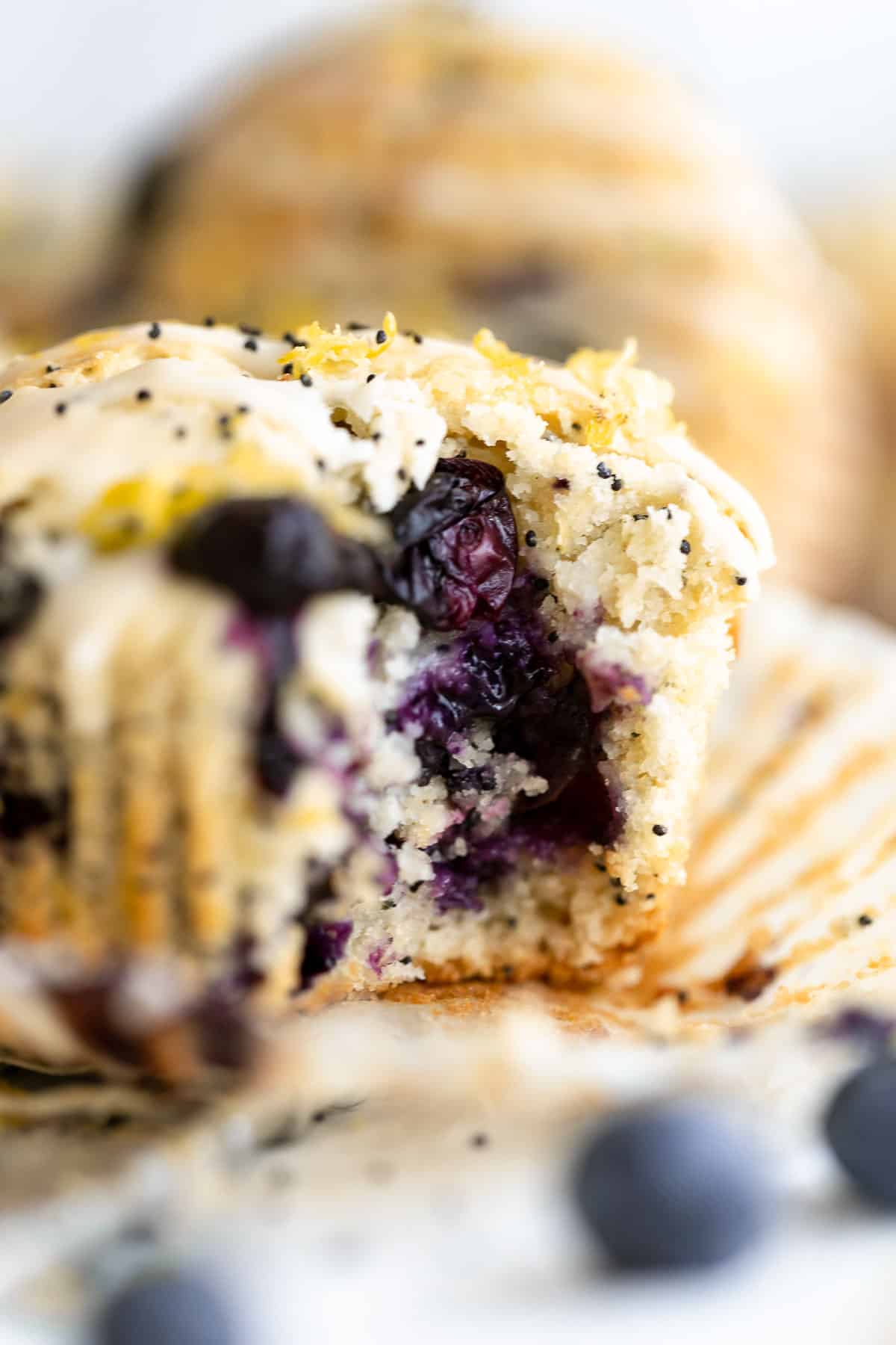 Gluten free lemon blueberry muffins with poppy seeds and a bite taken out to show texture.