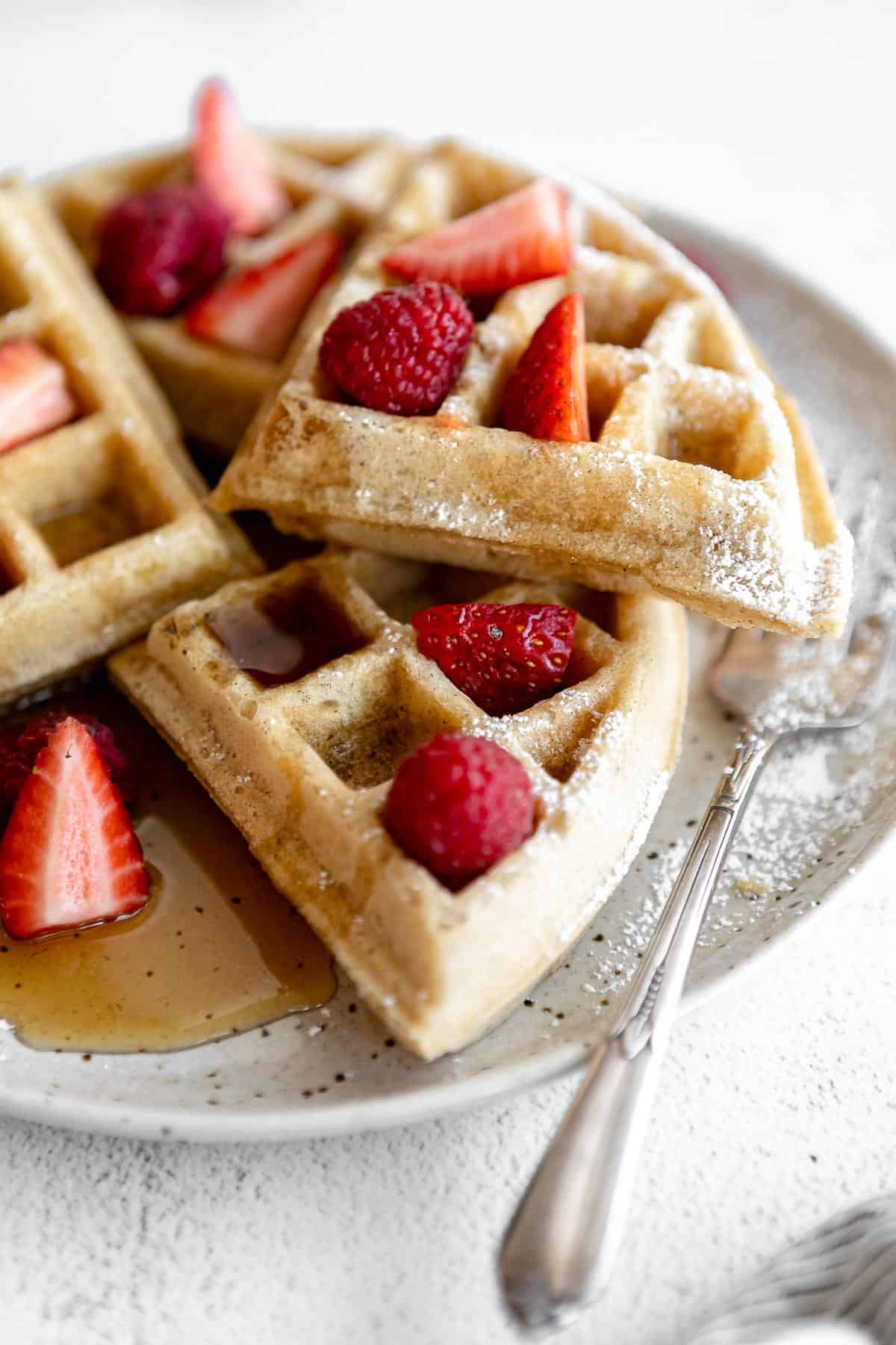 gluten free waffles on a plate with powdered sugar and berries