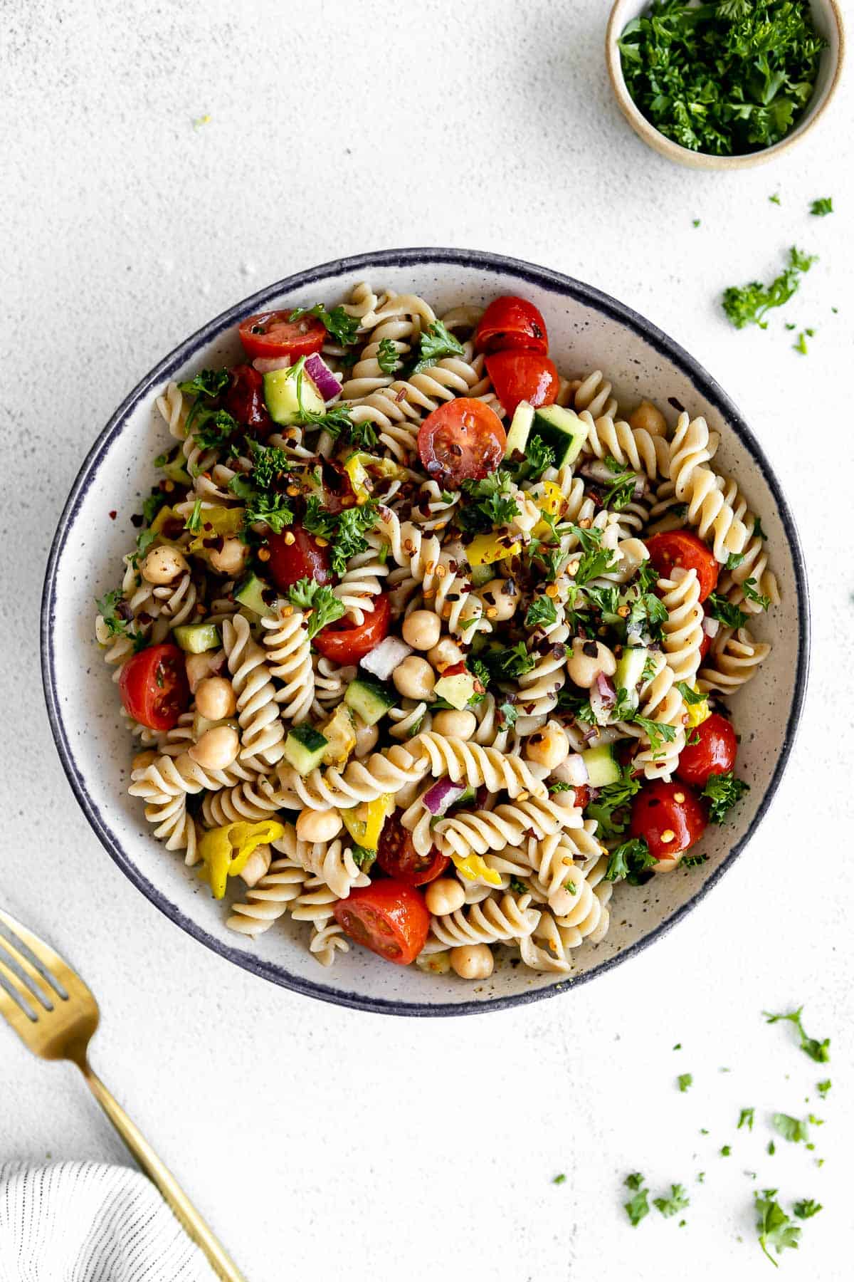 vegan chickpea pasta salad in a bowl with tomatoes and fresh herbs
