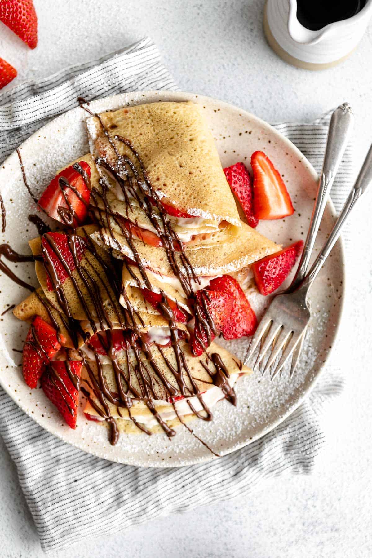 gluten free crepes folded on a plate with powdered sugar