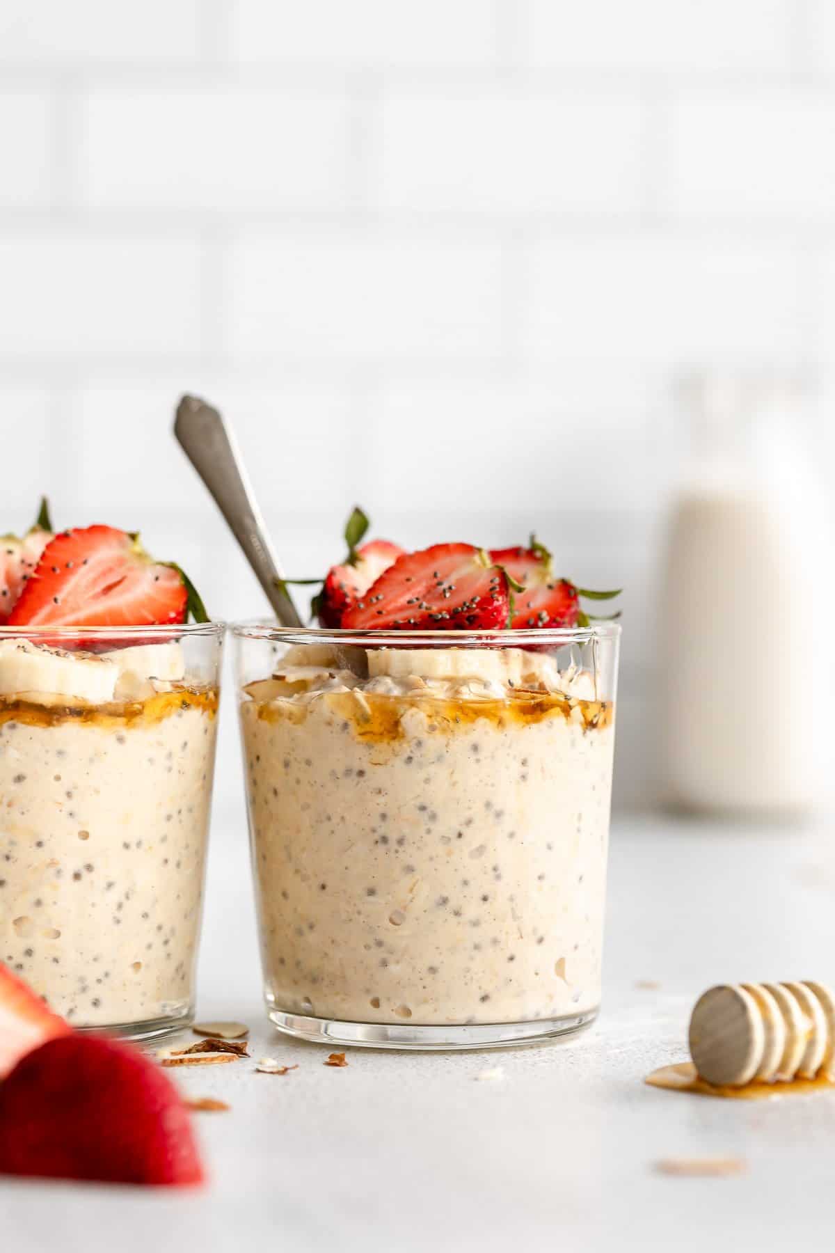 protein overnight oats in two glass jars with banana and strawberries