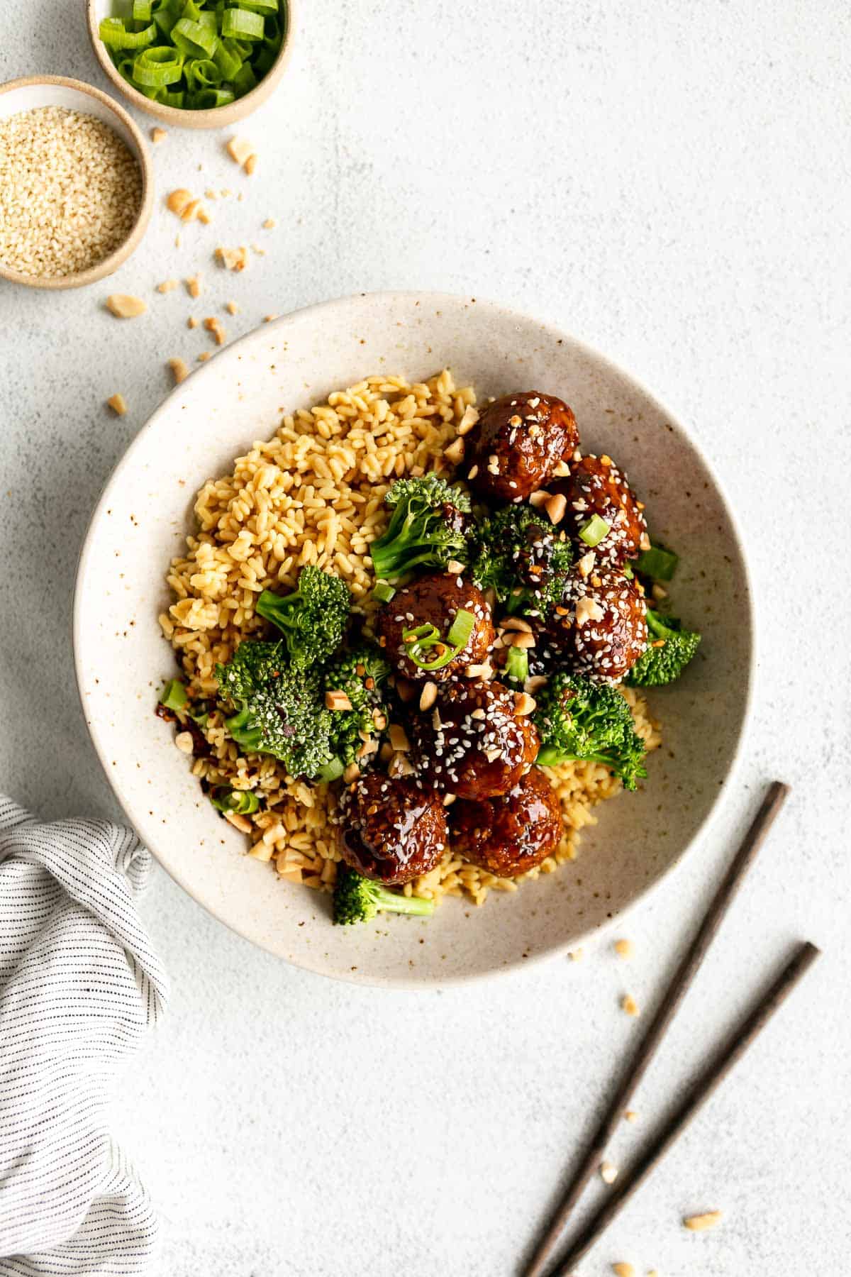 sesame chickpea meatballs in a bowl with rice and chopped peanuts