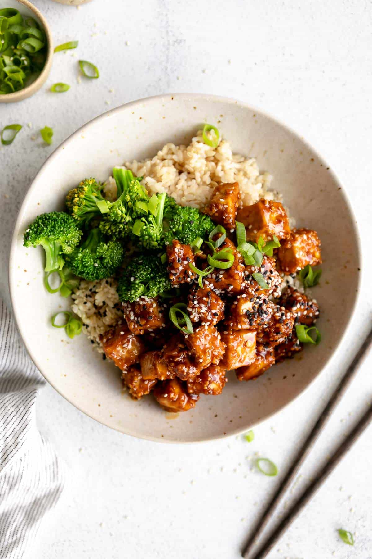 sesame tofu in a bowl with broccoli and rice