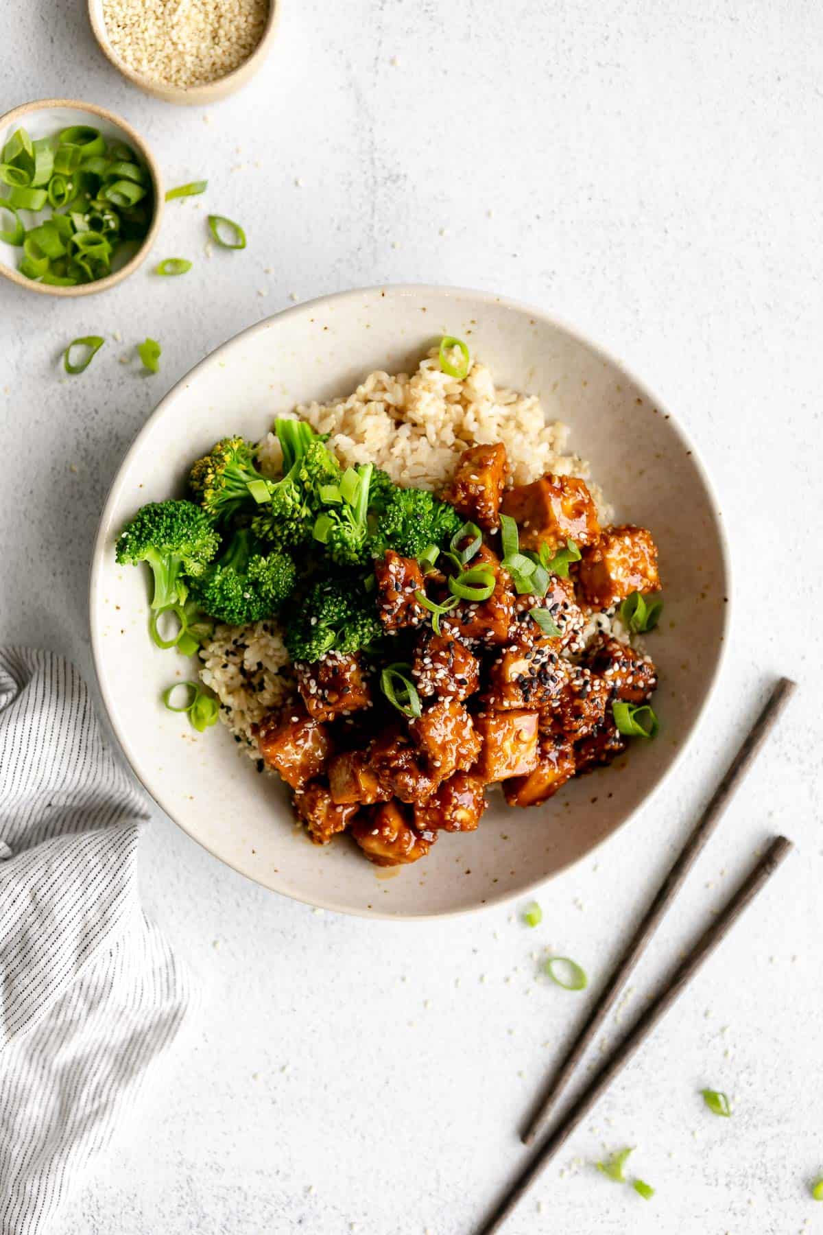 crispy baked sesame tofu in a bowl with broccoli and chopsticks