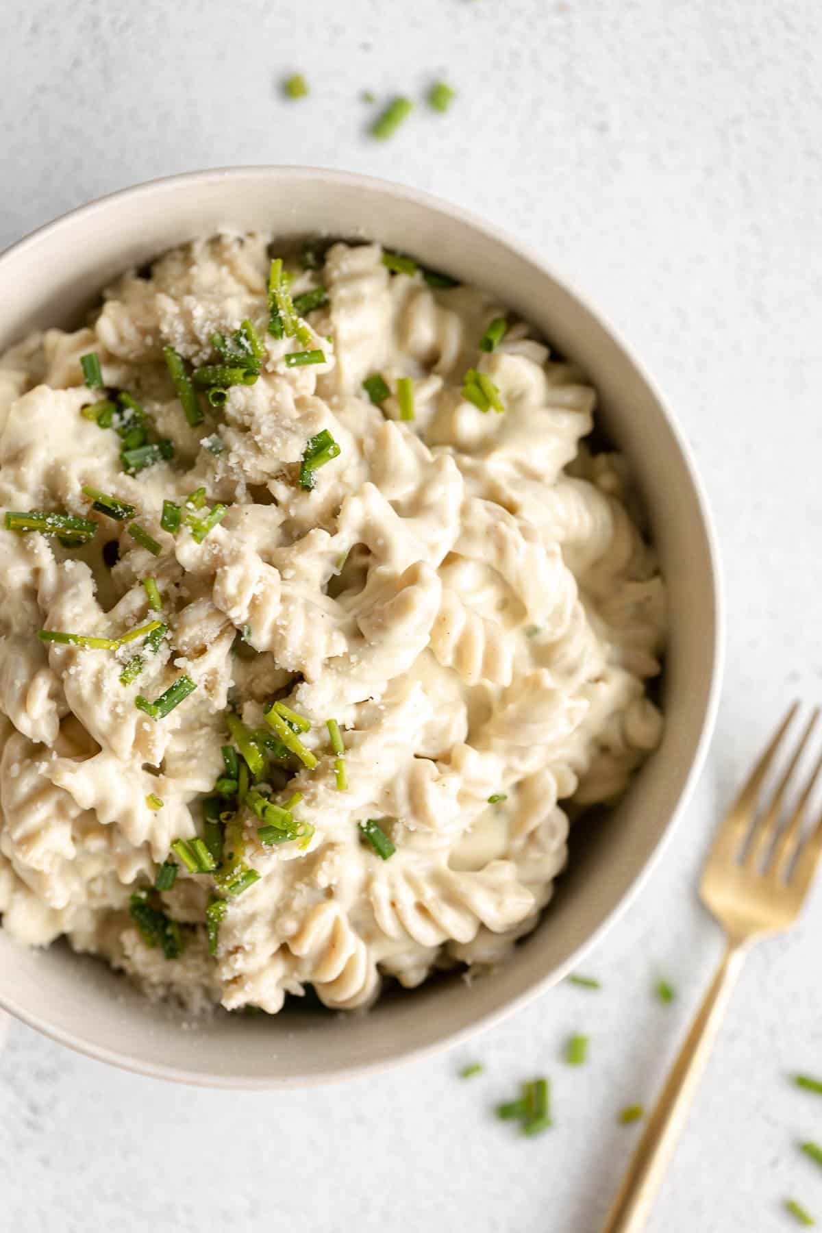 vegan cauliflower mac and cheese in a bowl with a fork on the side