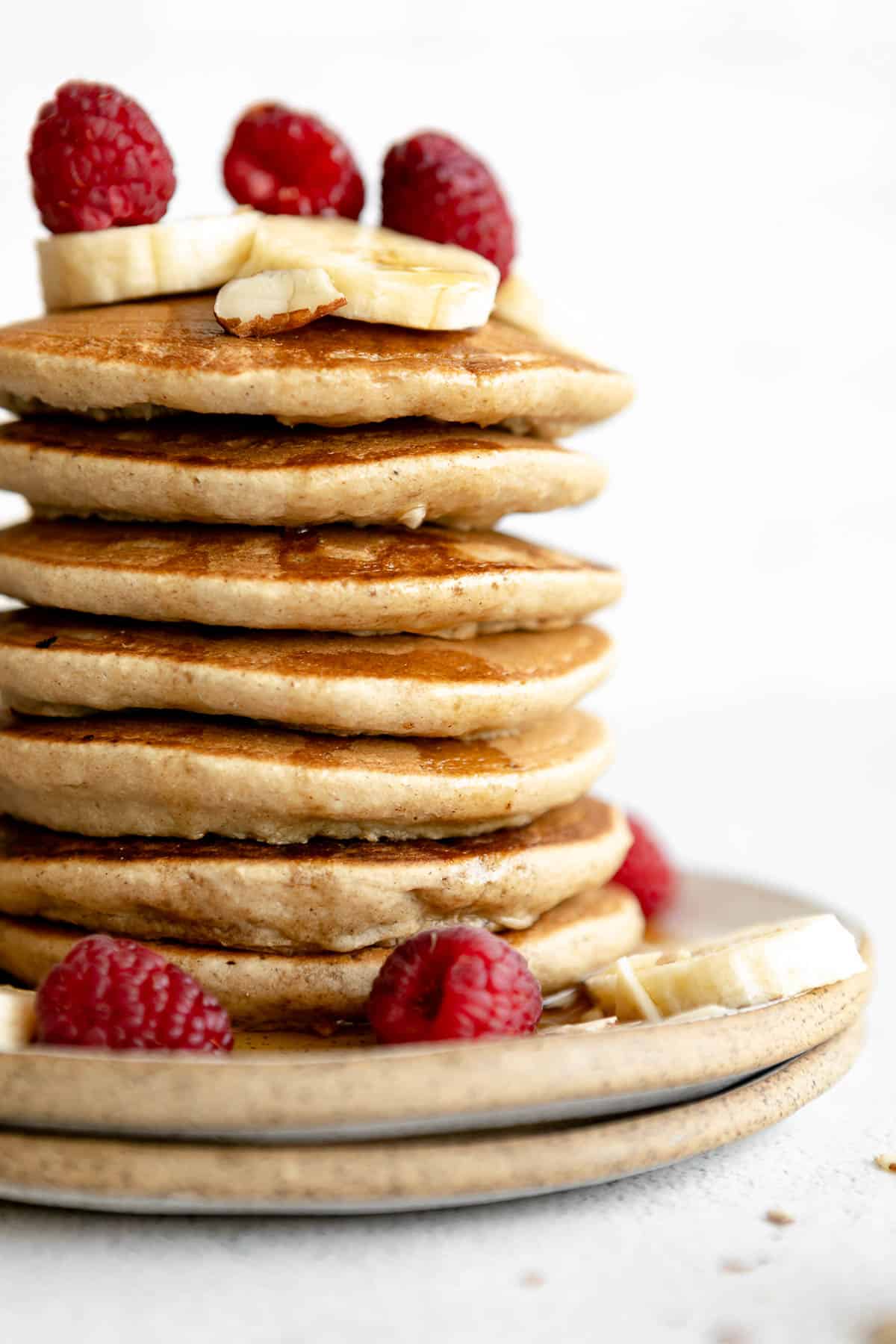 tall stack of fluffy vegan chickpea flour pancakes with banana and maple syrup