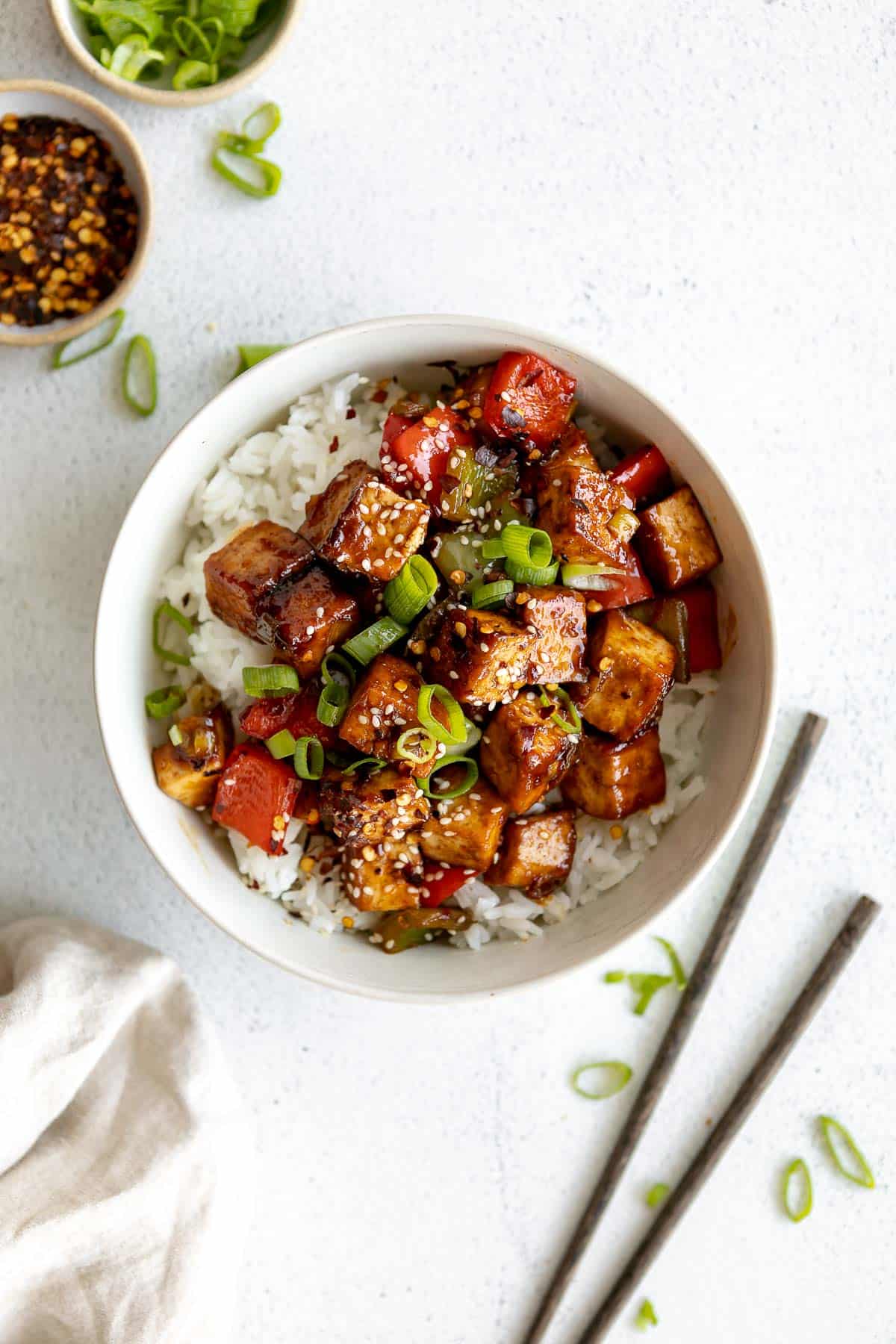 kung pao tofu in a bowl with sesame seeds served over white rice