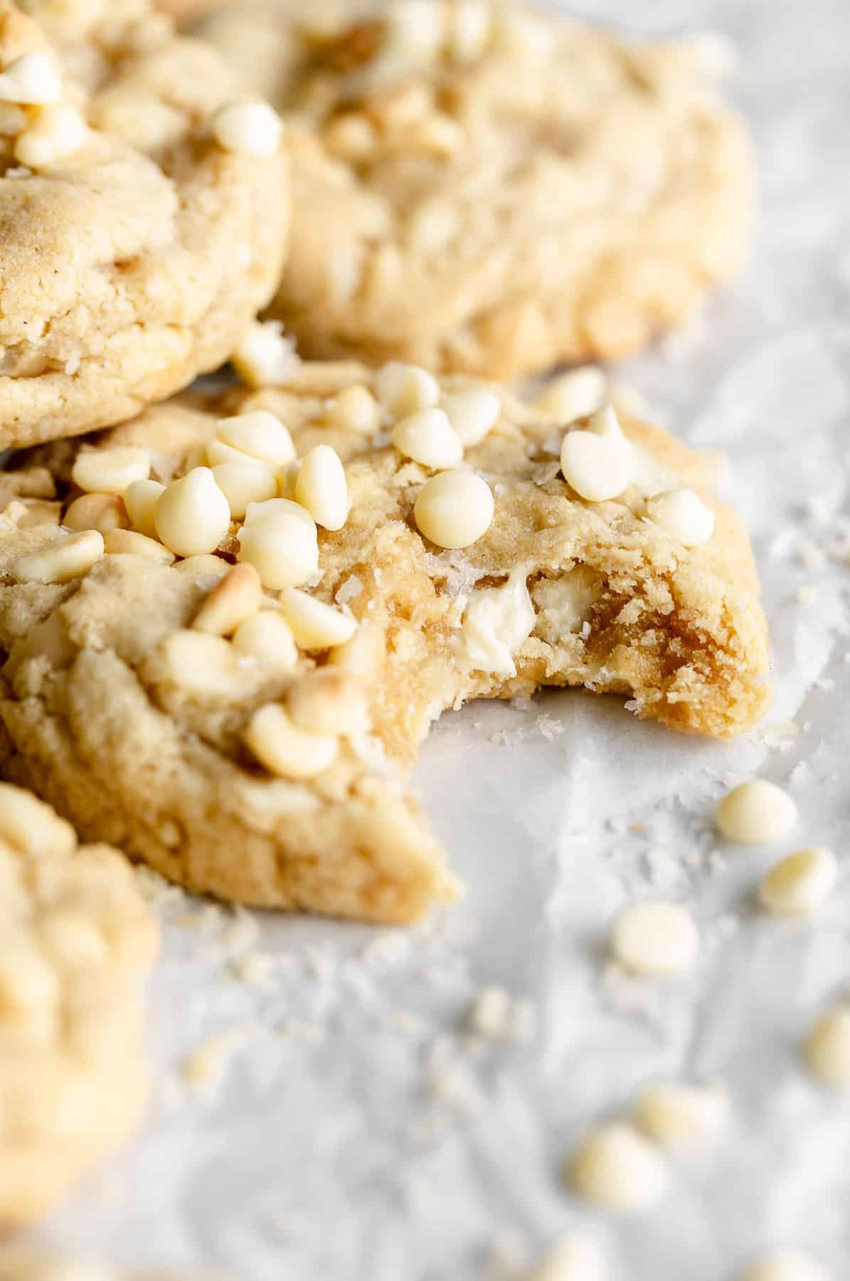 one bite taken out of the gluten free white chocolate macadamia nut cookie with sea salt