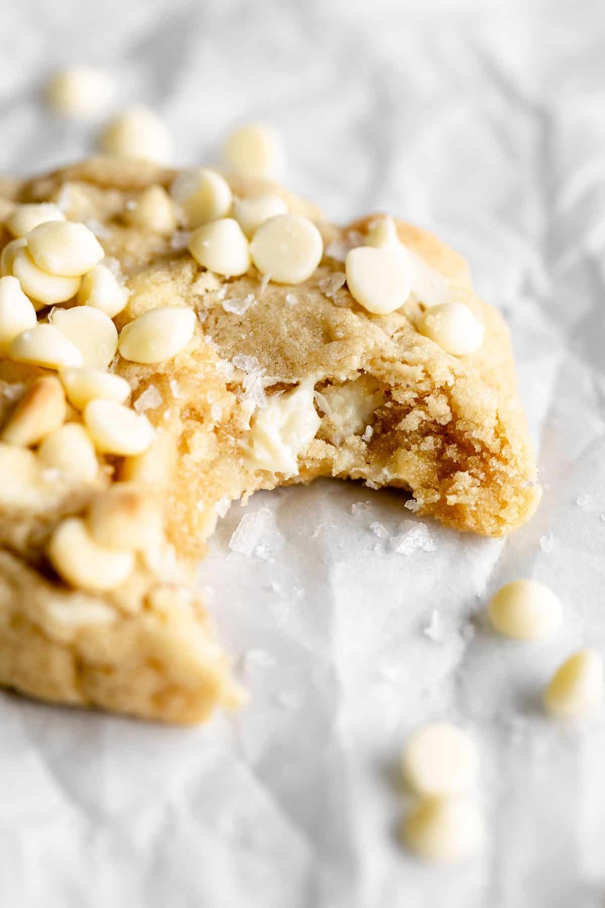 white chocolate macadamia nut cookies with a bit taken out on parchment paper
