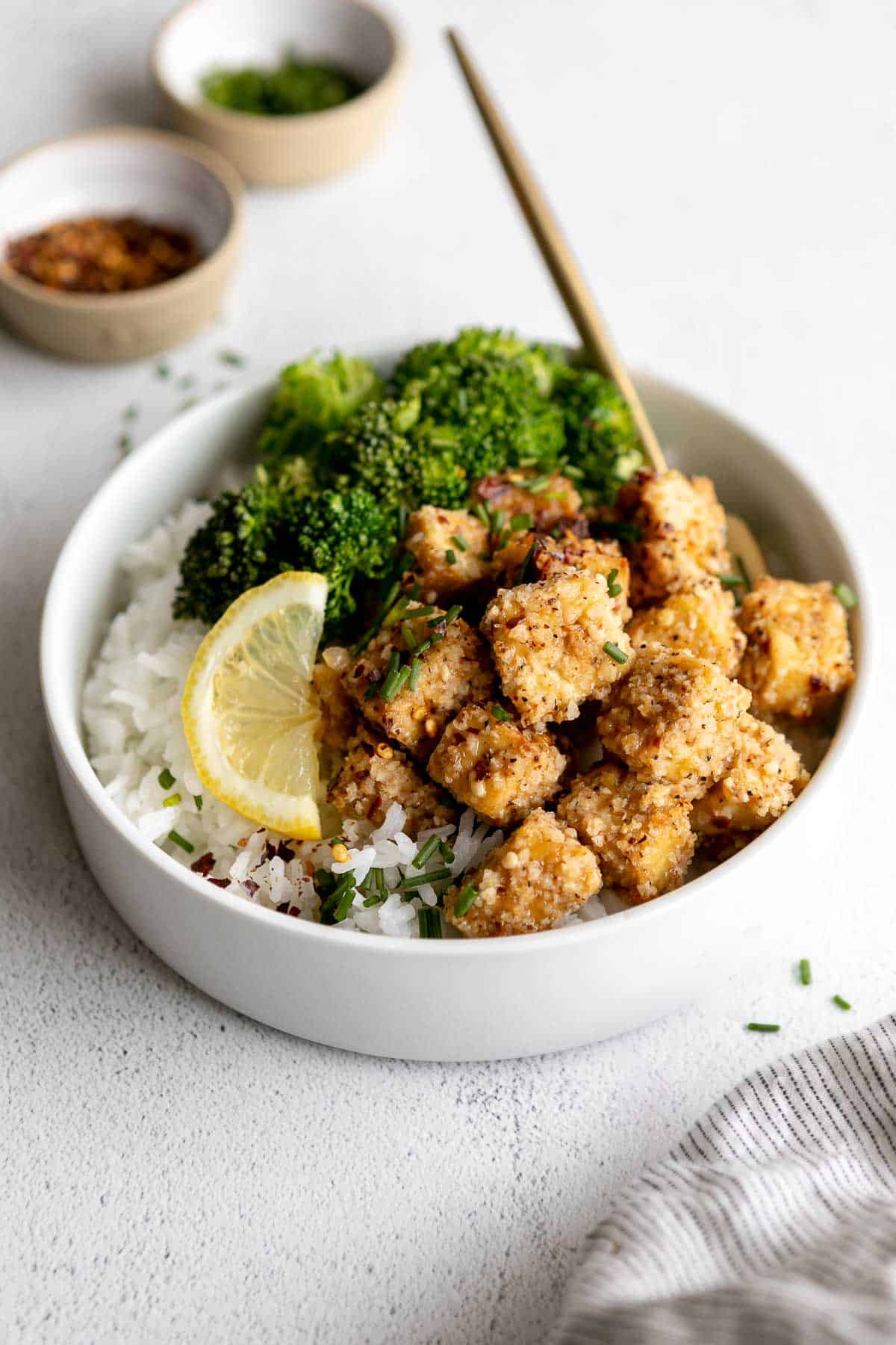 baked lemon pepper tofu in a bowl with rice and broccoli