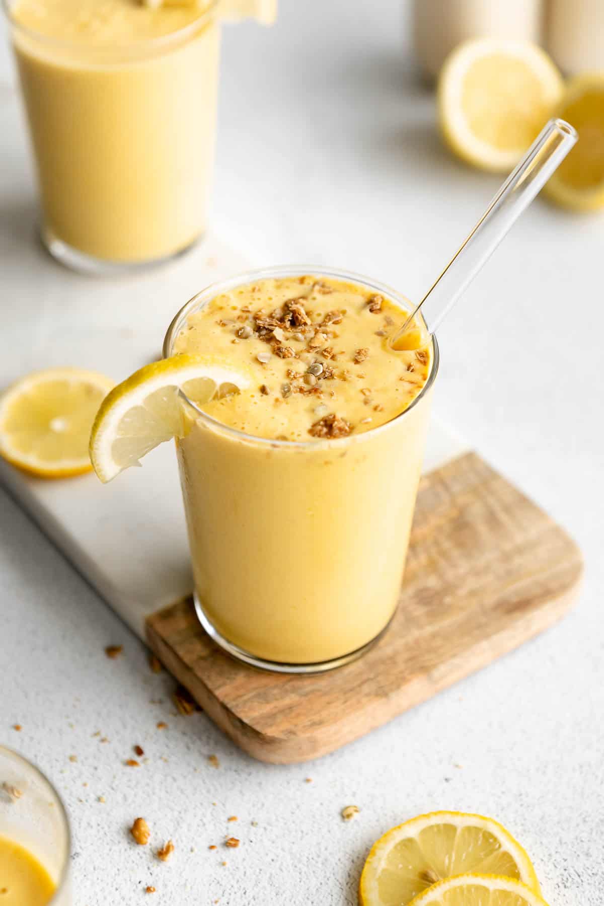 pineapple lemon smoothie in a glass with lemon wedges