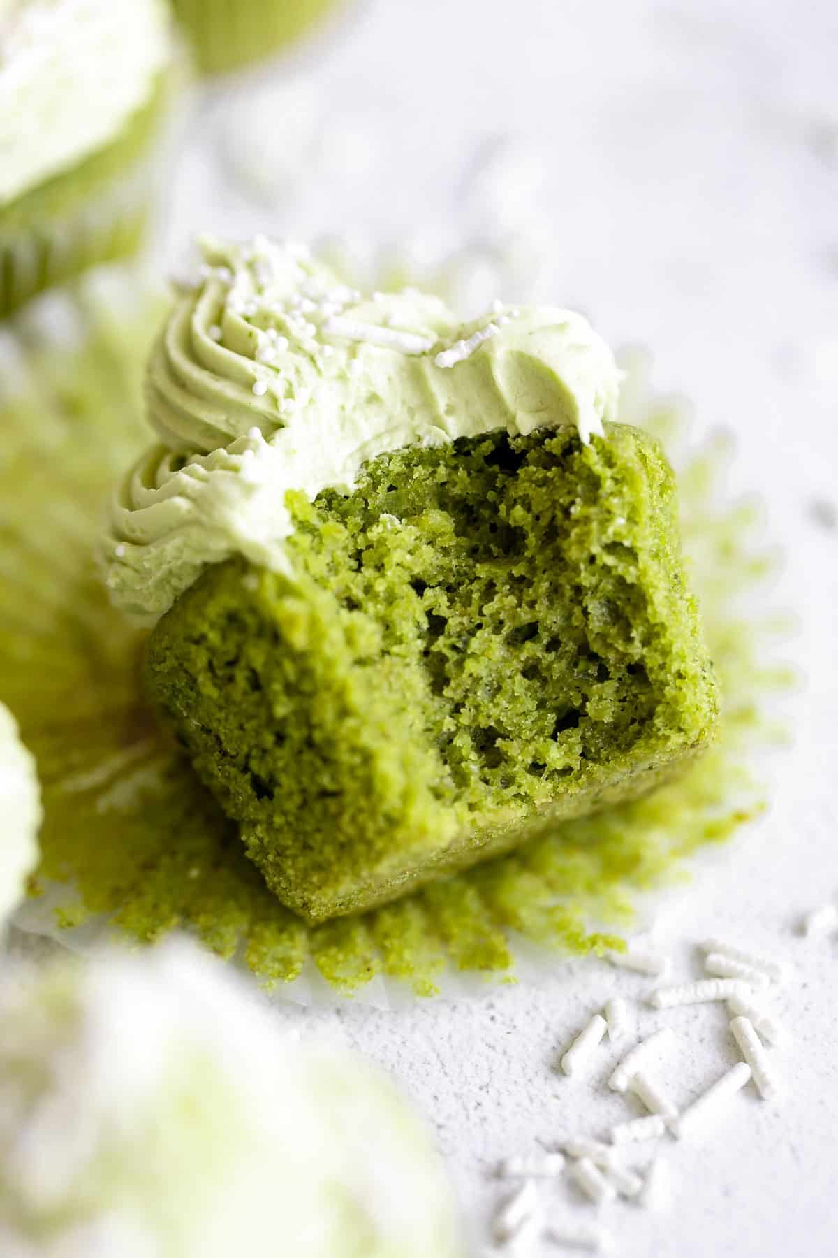 vanilla matcha cupcakes with a bite taken out to show fluffy texture
