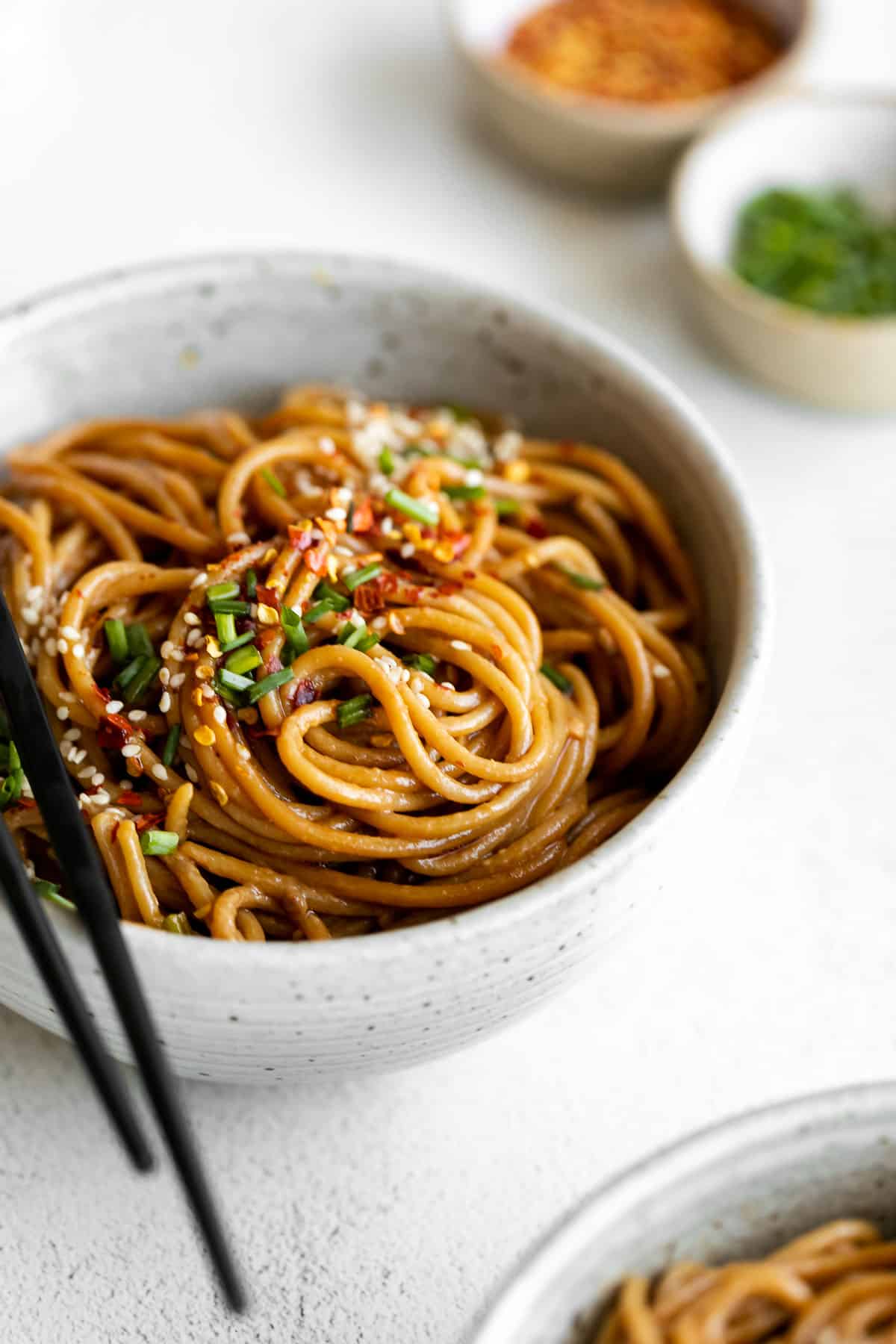 Up close image of garlic sesame noodles with chopsticks on the side.