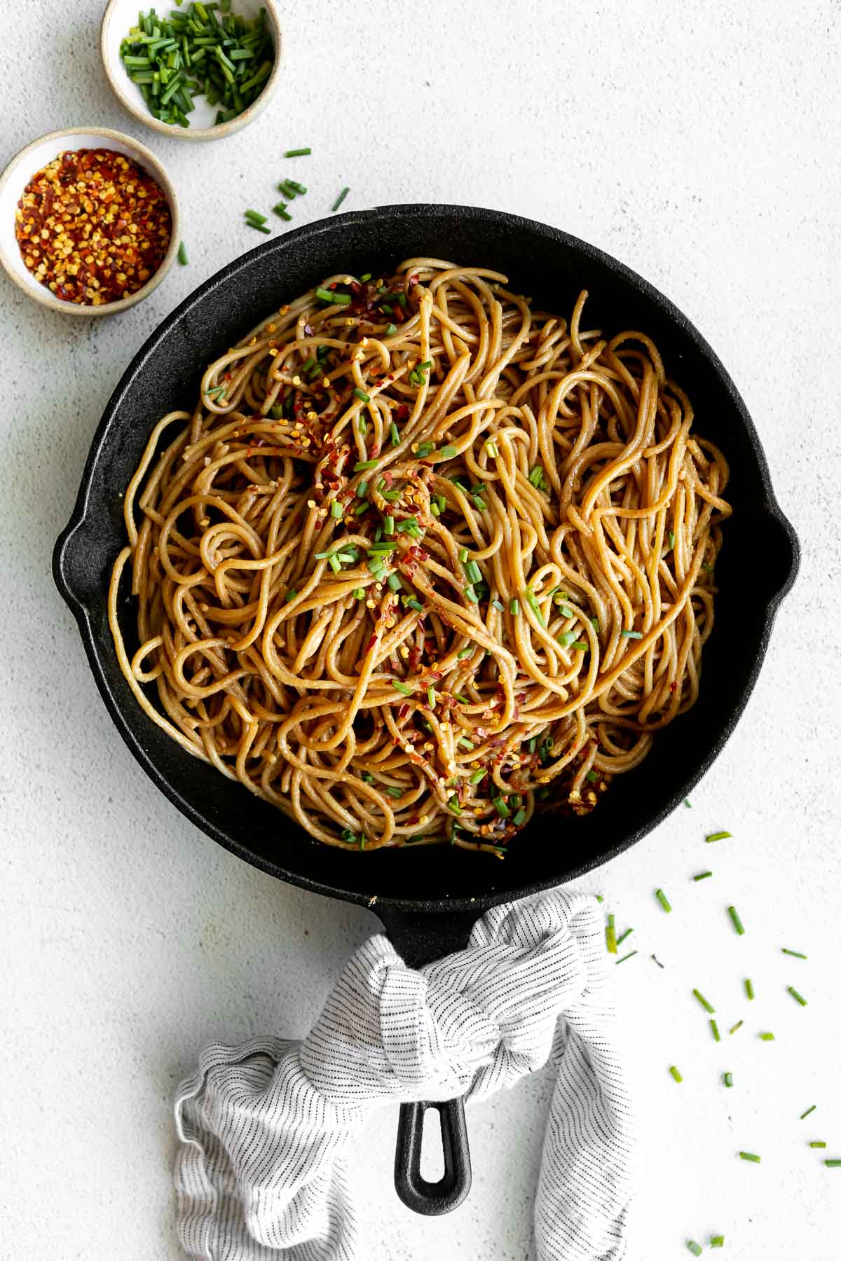 Skillet with the noodles and a large spoon on the side.