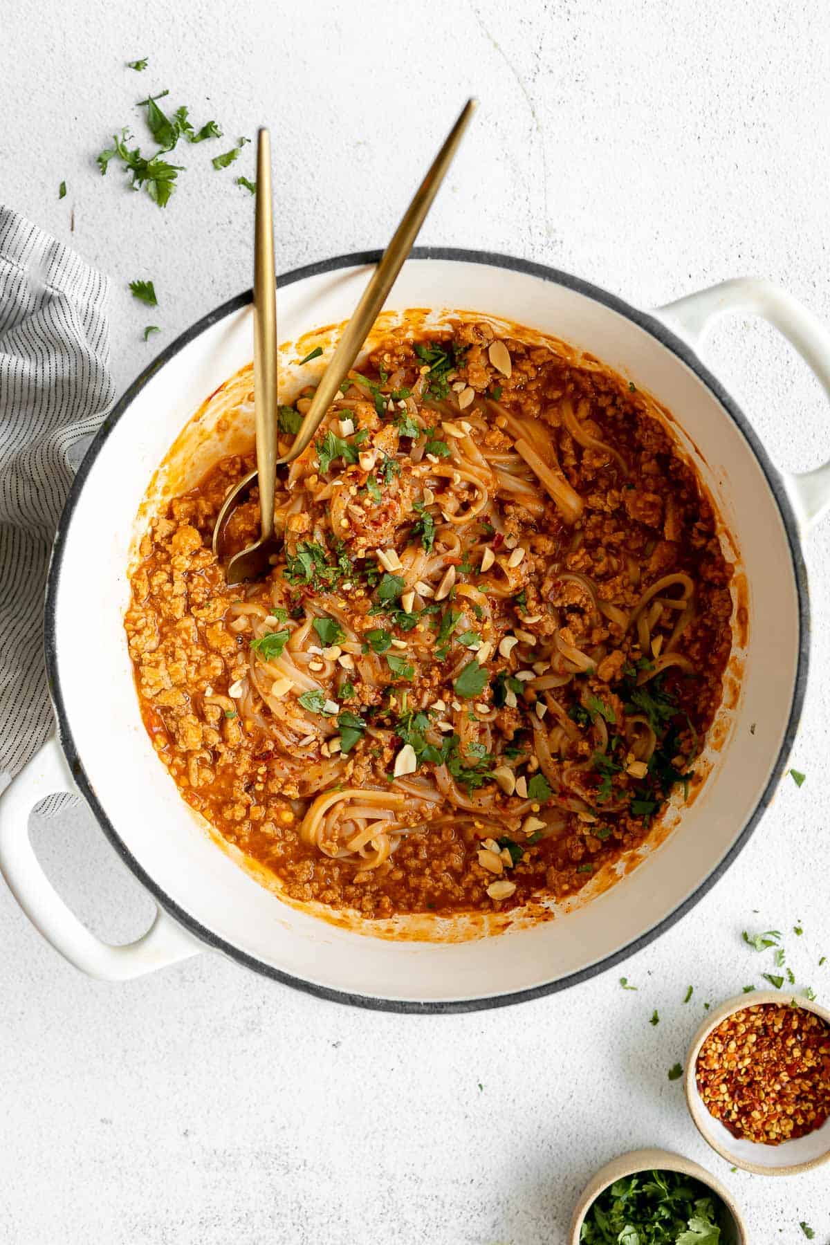 spicy chicken noodles in a pot with cilantro and peanuts