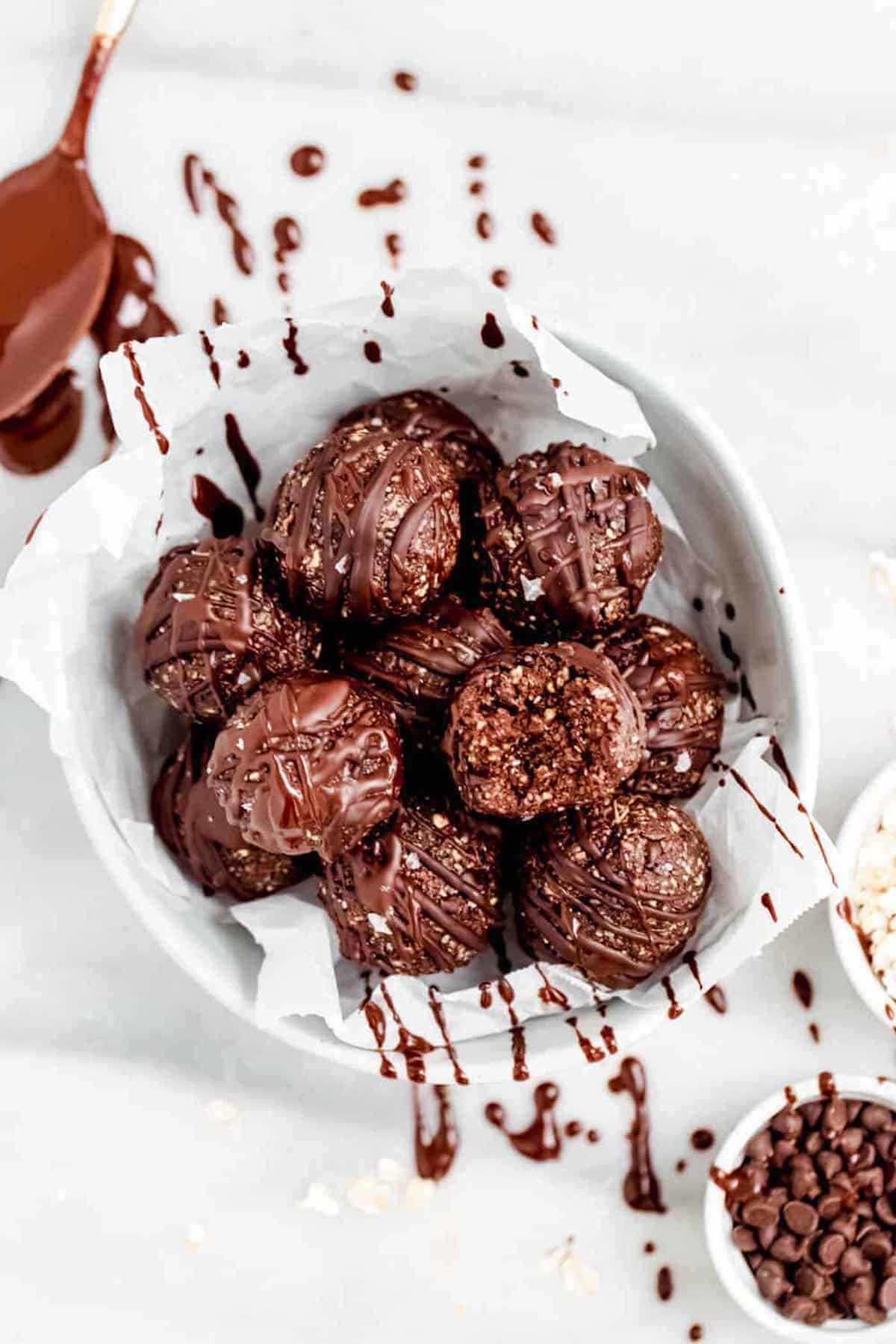 Chocolate coconut bliss balls in a bowl with chocolate chips. 