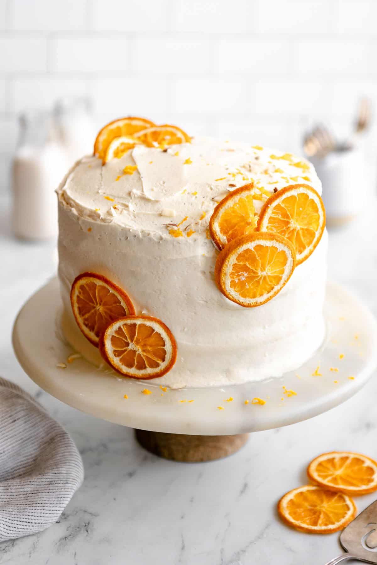 gluten free orange cake on a cake stand with orange slices