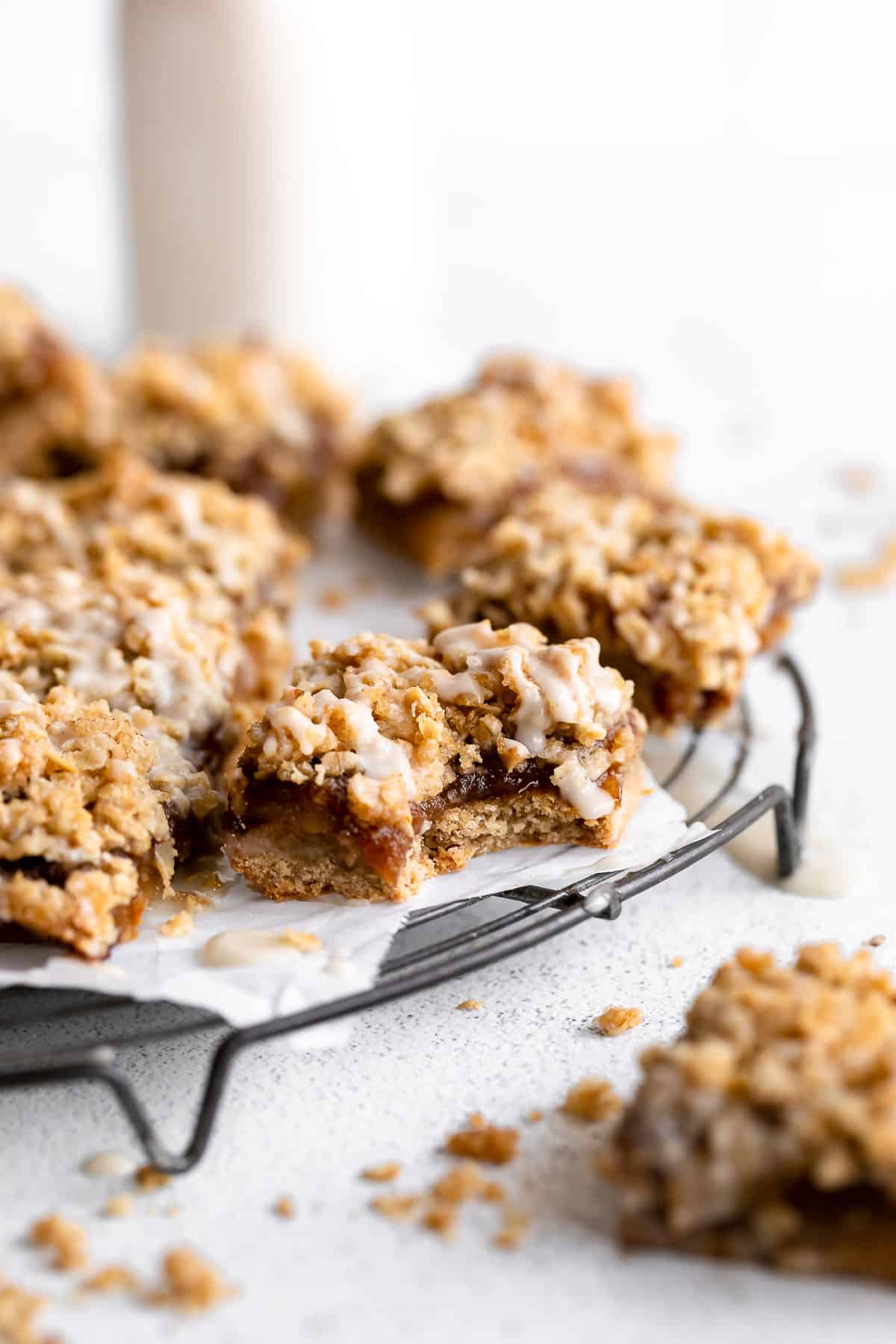 apple pie crumble bars on a wire rack with milk in the back