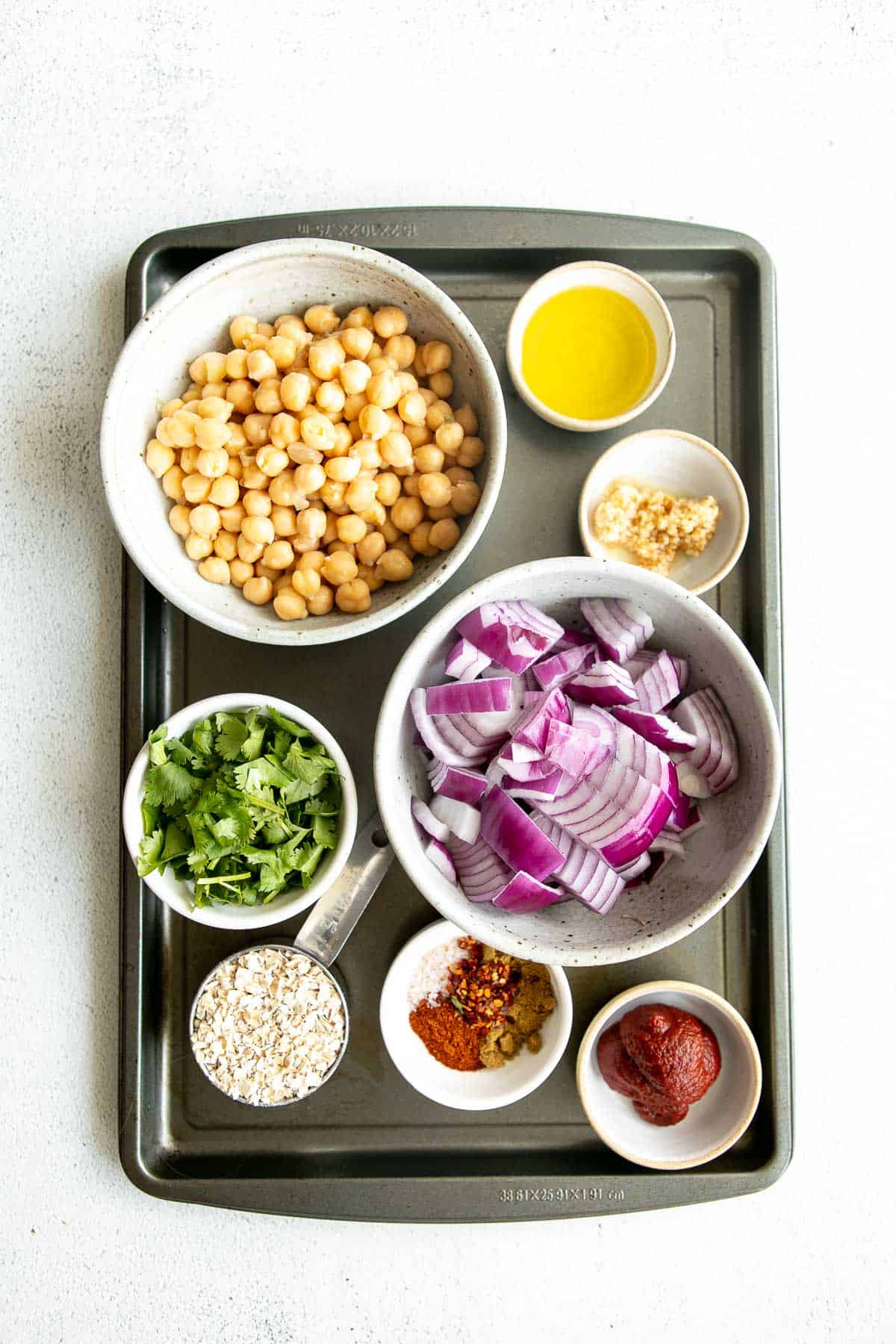 ingredients for the burgers in bowls on a baking pan