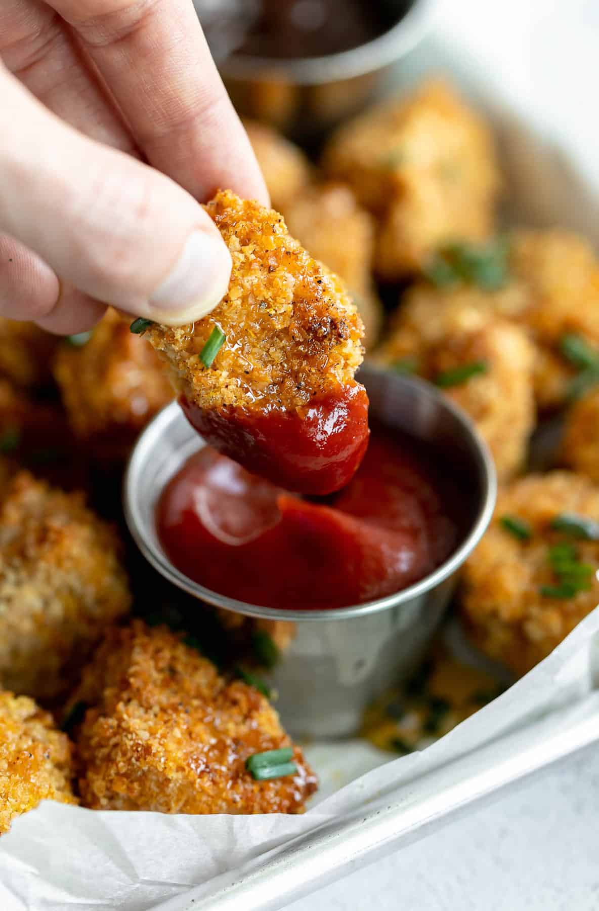 dipping the vegan tofu chicken nugget in ketchup