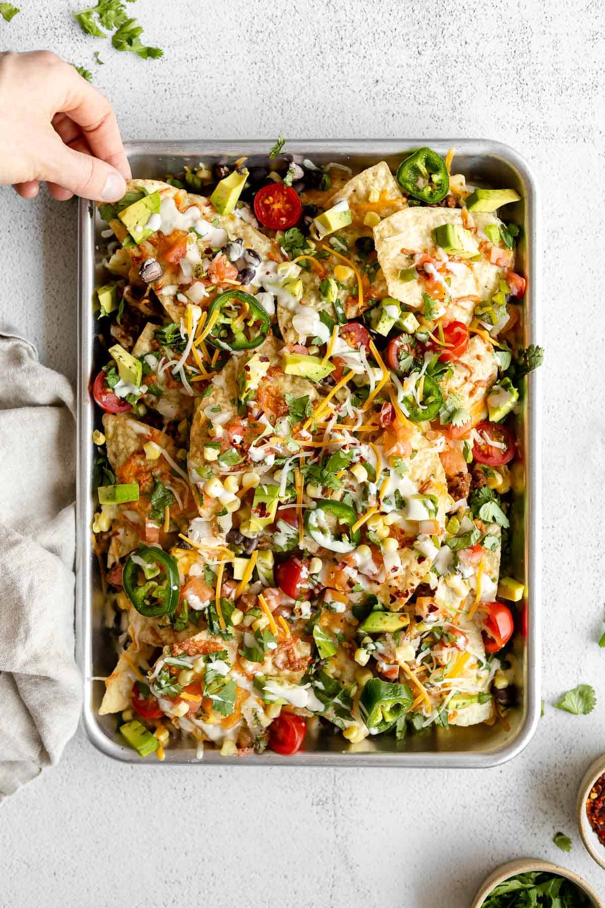 vegan and vegetarian nachos on a baking sheet with cheese and tomatoes