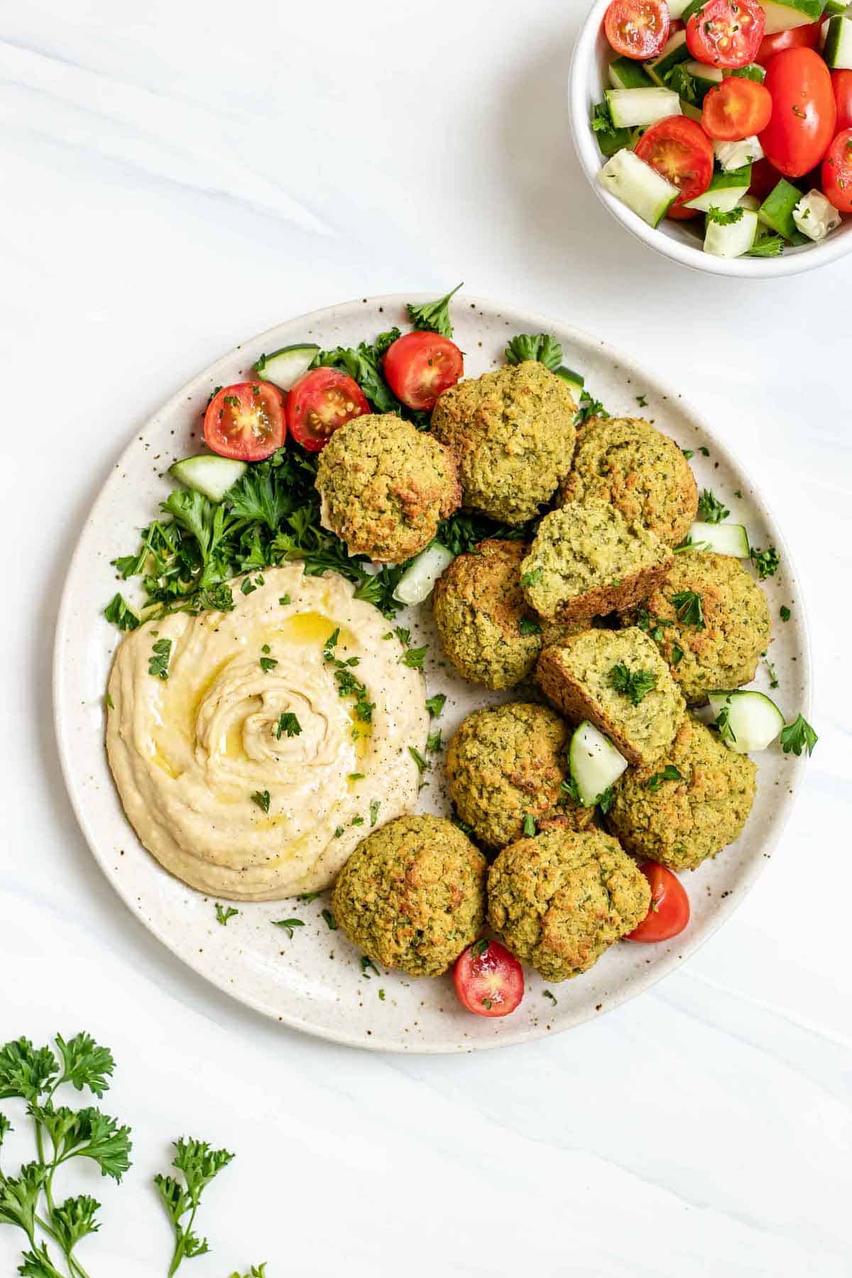 Plate with baked falafel, hummus, cucumber and tomatoes.