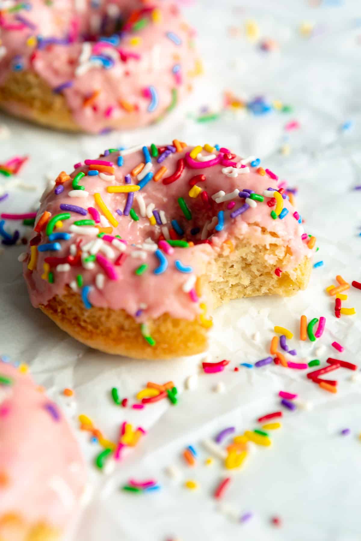 gluten free donuts with a bite taken out with vanilla frosting