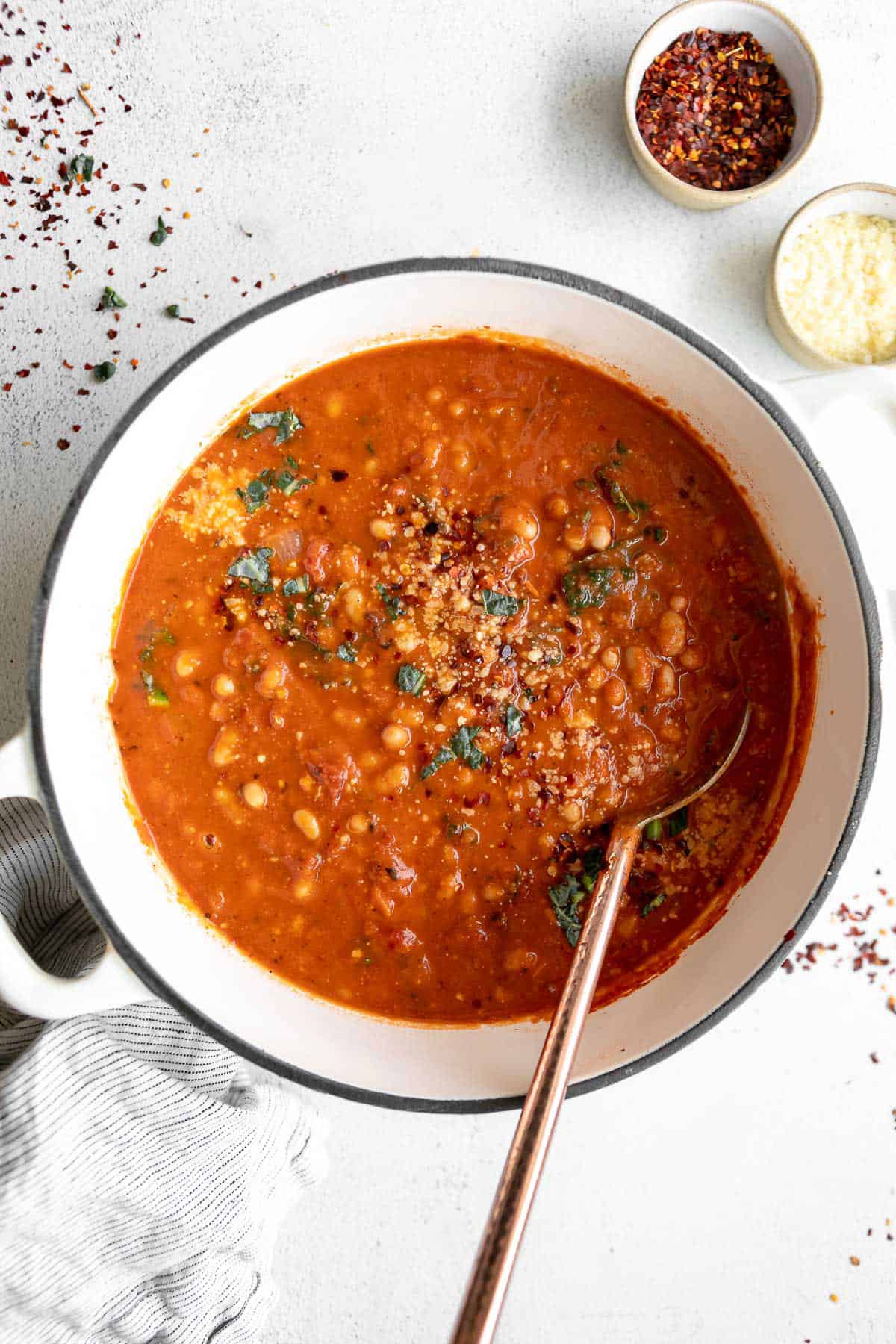 vegan white bean tomato soup in a large pot with parmesan