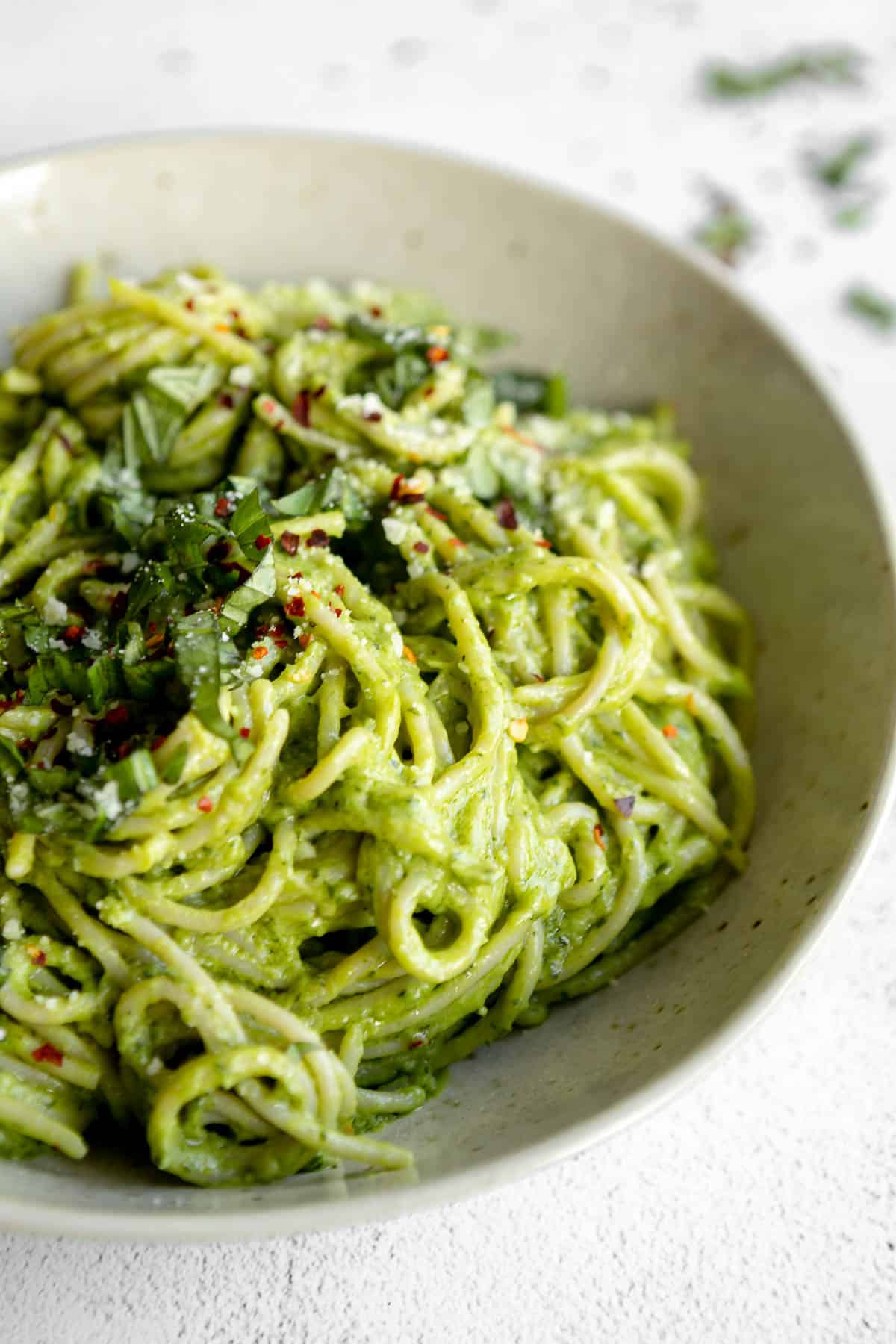 Avocado pasta in a bowl with red pepper flakes. 