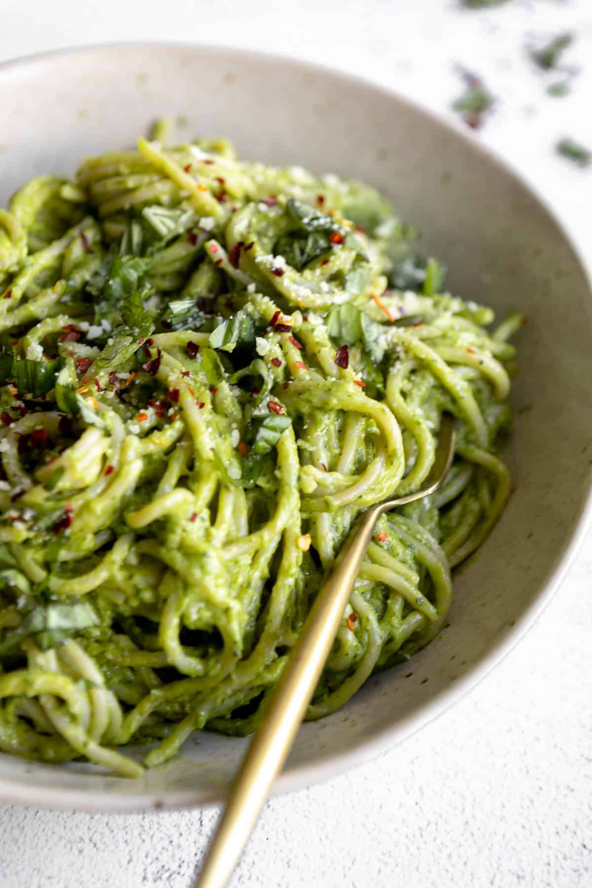 up close photo of the avocado pesto in a bowl with fresh basil