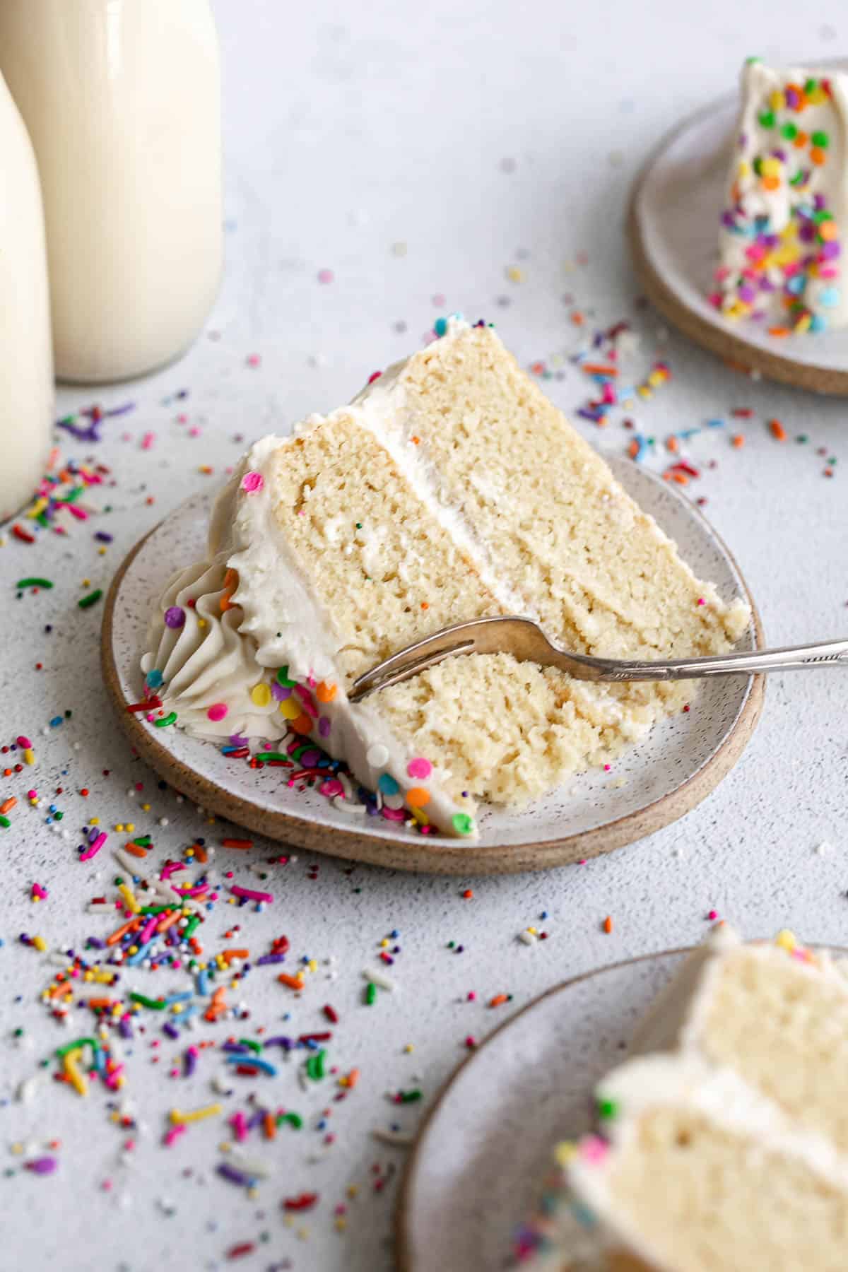 three slices of gluten free vanilla cake on plate with a fork on the side