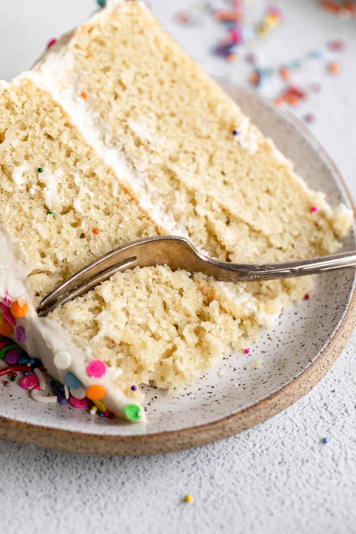 slice of gluten free vanilla cake with a fork on the side