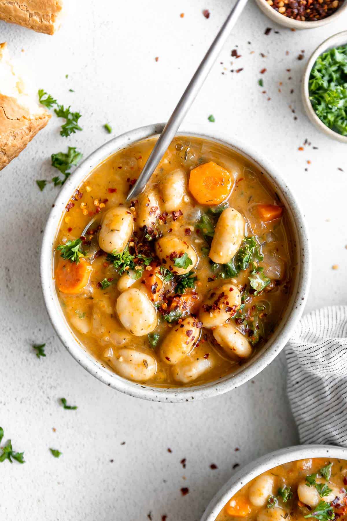 tuscan vegan gnocchi soup in a bowl with a spoon on the side
