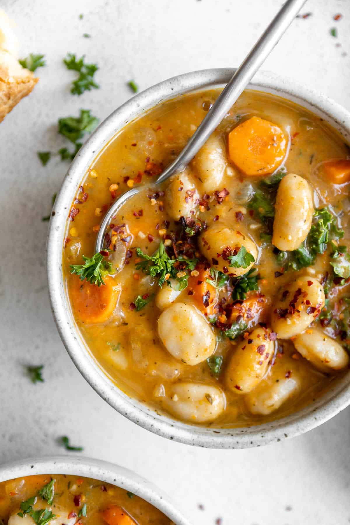 vegan tuscan gnocchi soup in a bowl with carrots and parsley