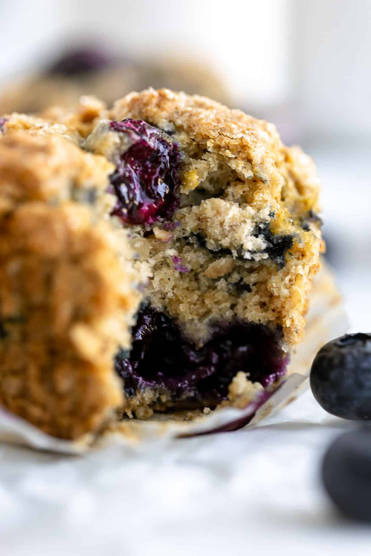 vegan blueberry oatmeal muffins with a bite taken out to show texture