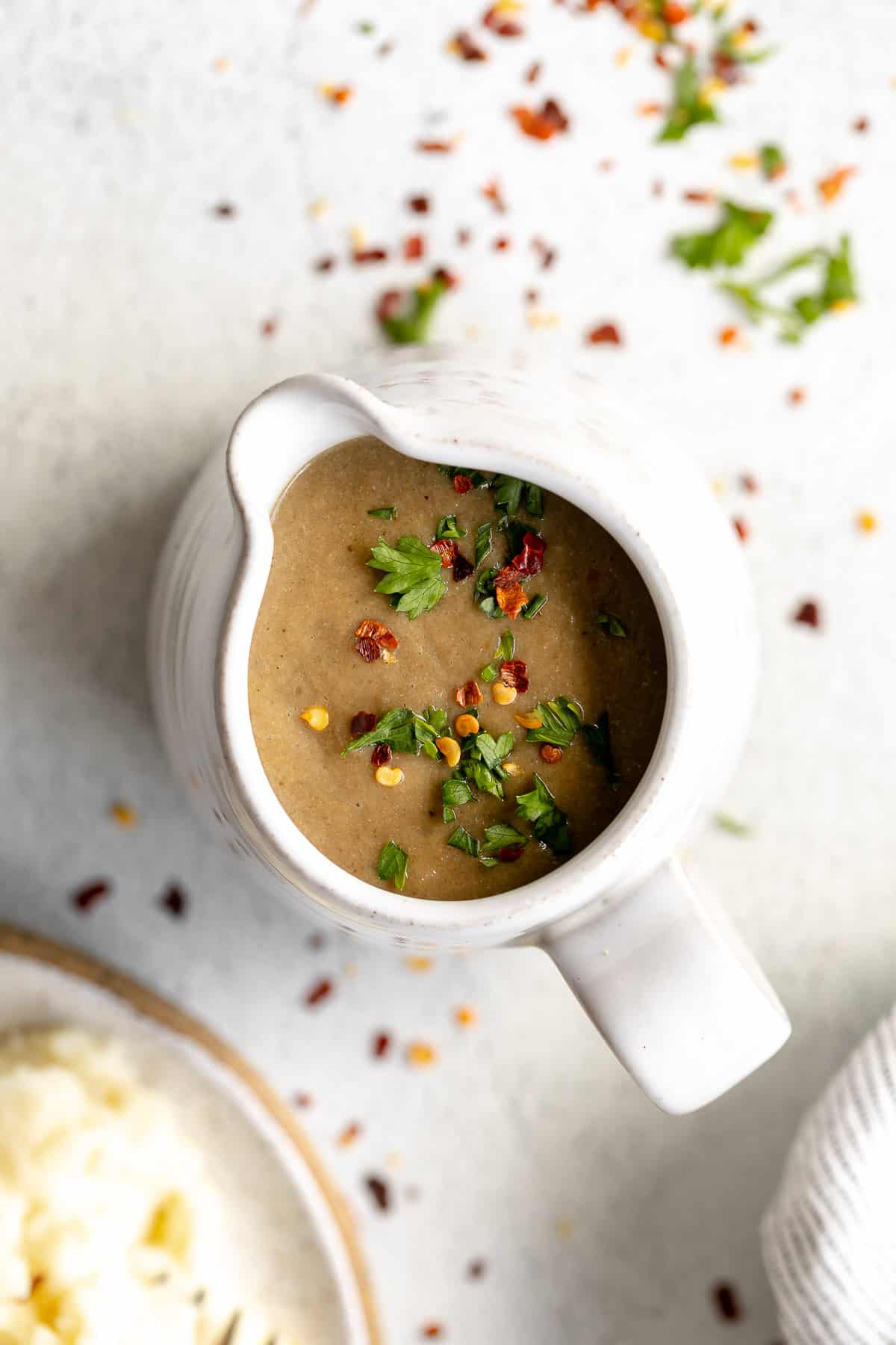 vegan mushroom gravy in a pitcher with herbs on top
