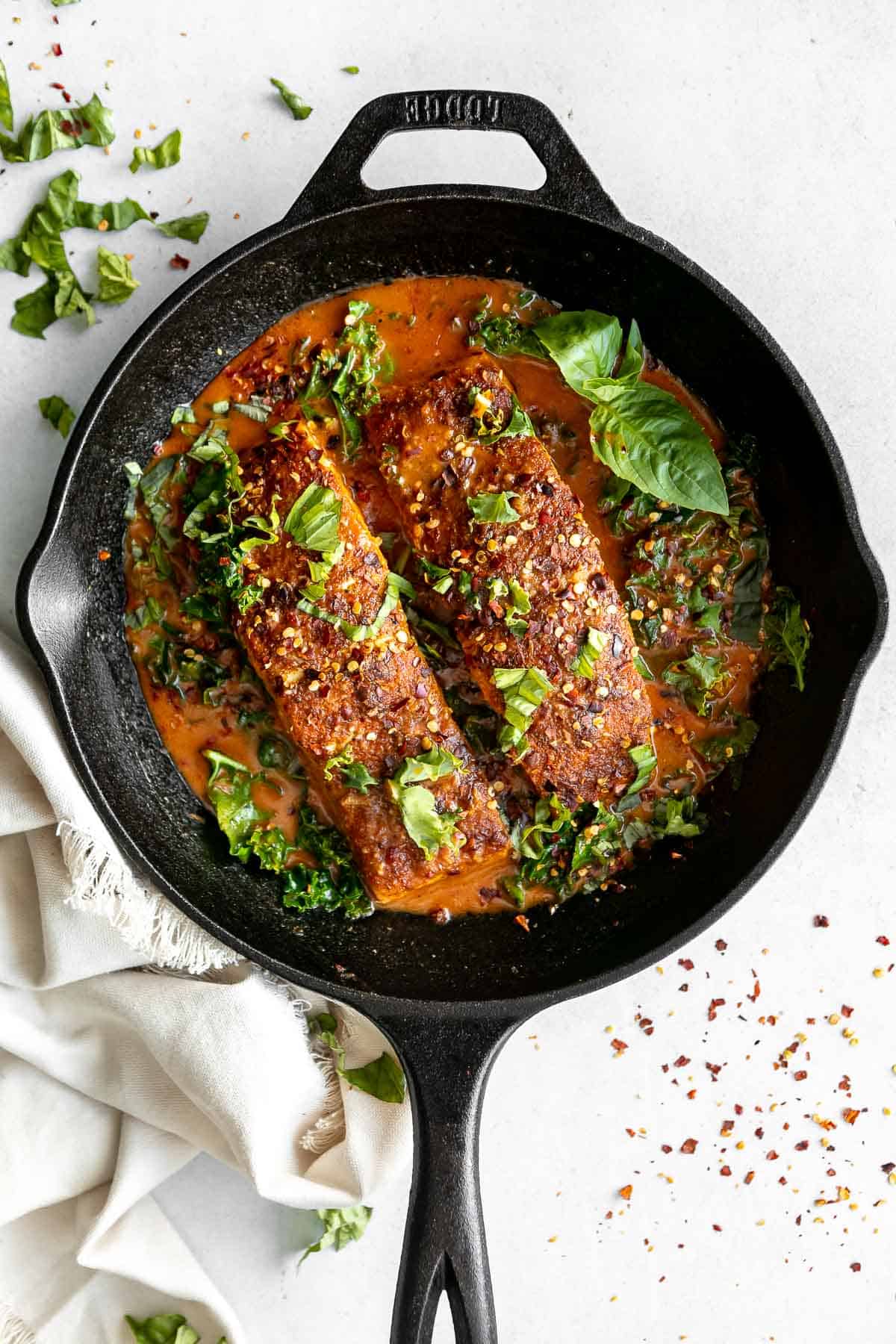 Thai coconut curry salmon in a pan with fresh basil 