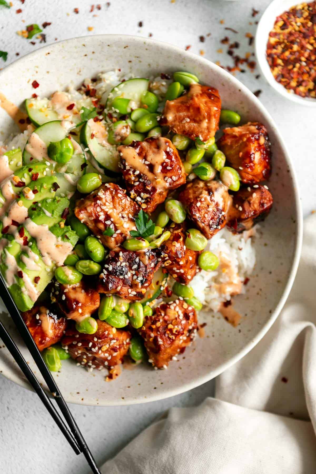 sriracha salmon cut into cubes in a bowl with edamame
