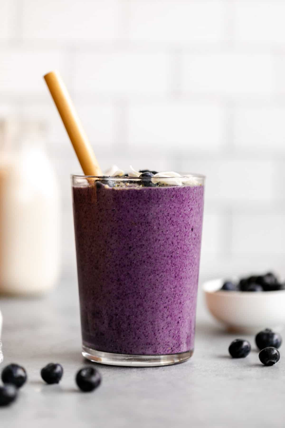 blueberry avocado smoothie in a glass with blueberries on the side