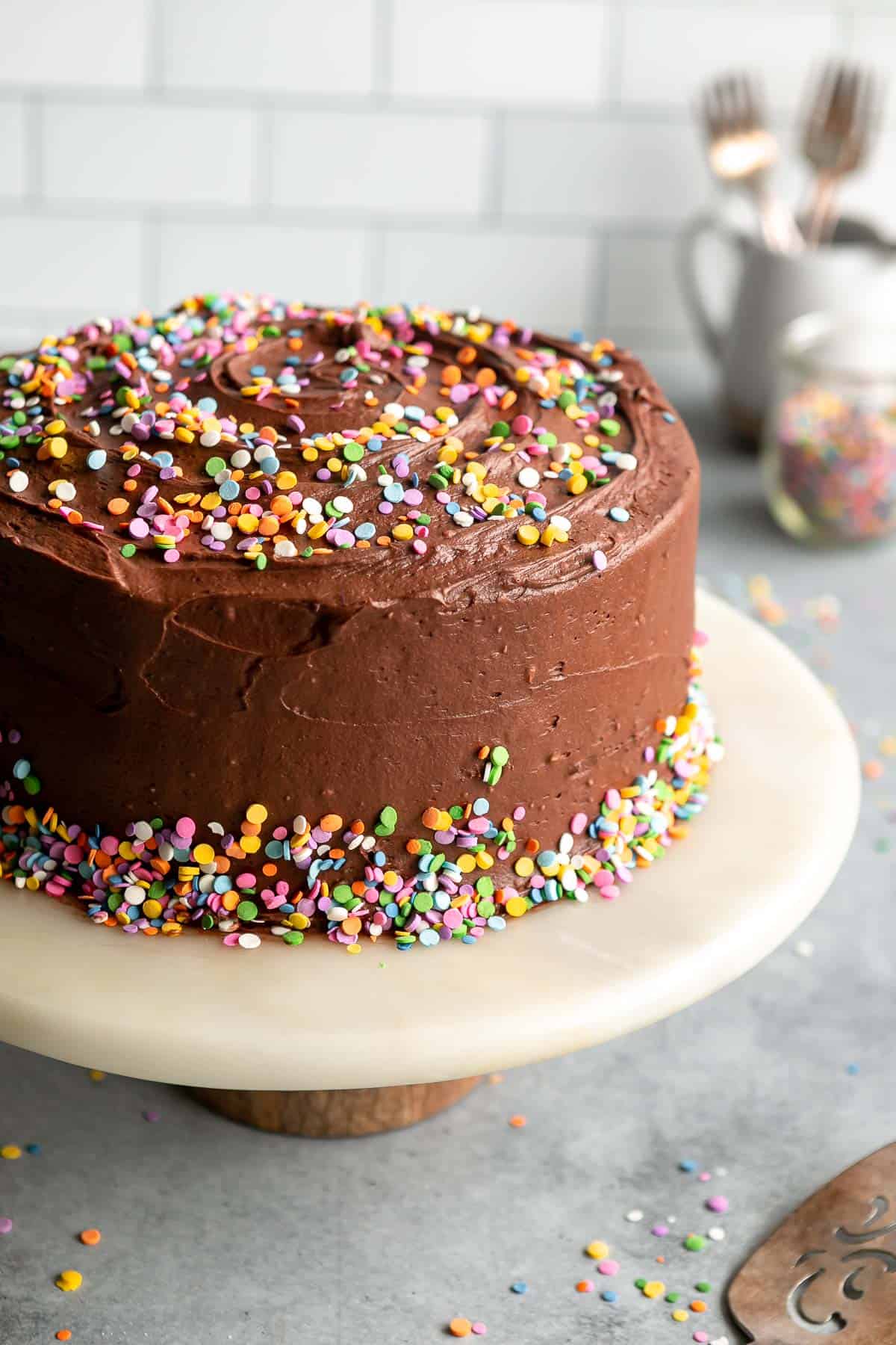 dairy free birthday cake on a cake plate with sprinkles 