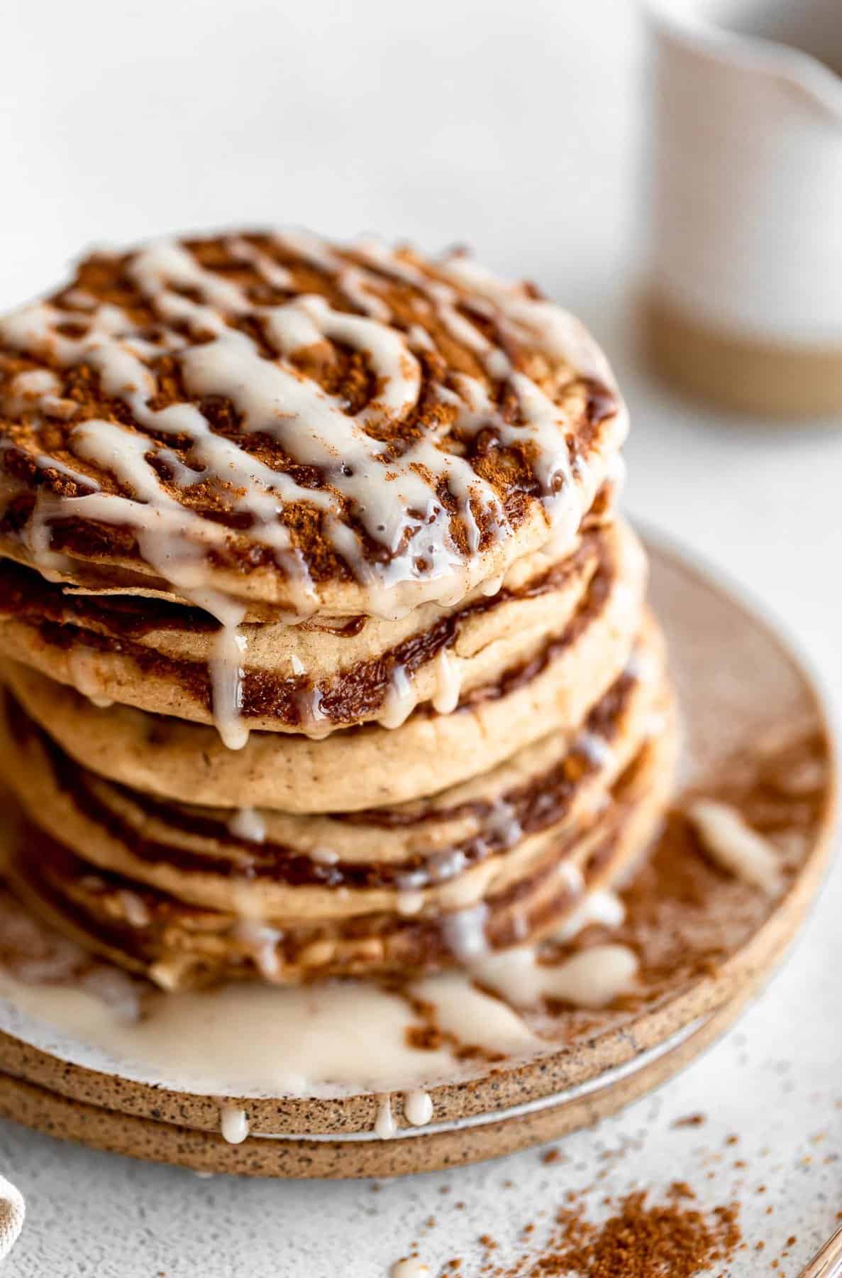 stack of cinnamon roll pancakes on a plate with glaze
