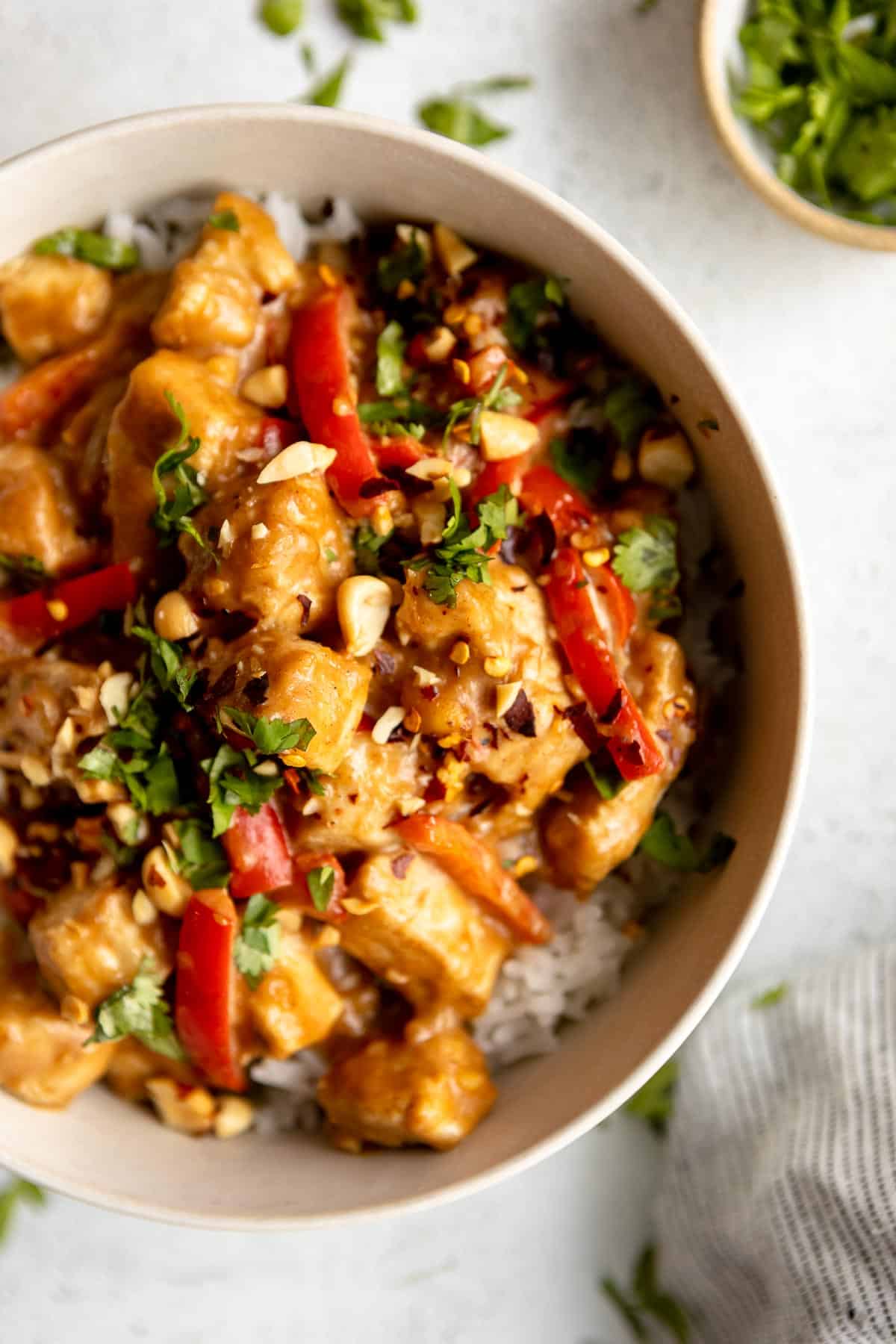 peanut butter chicken recipe in a bowl with peppers and cilantro
