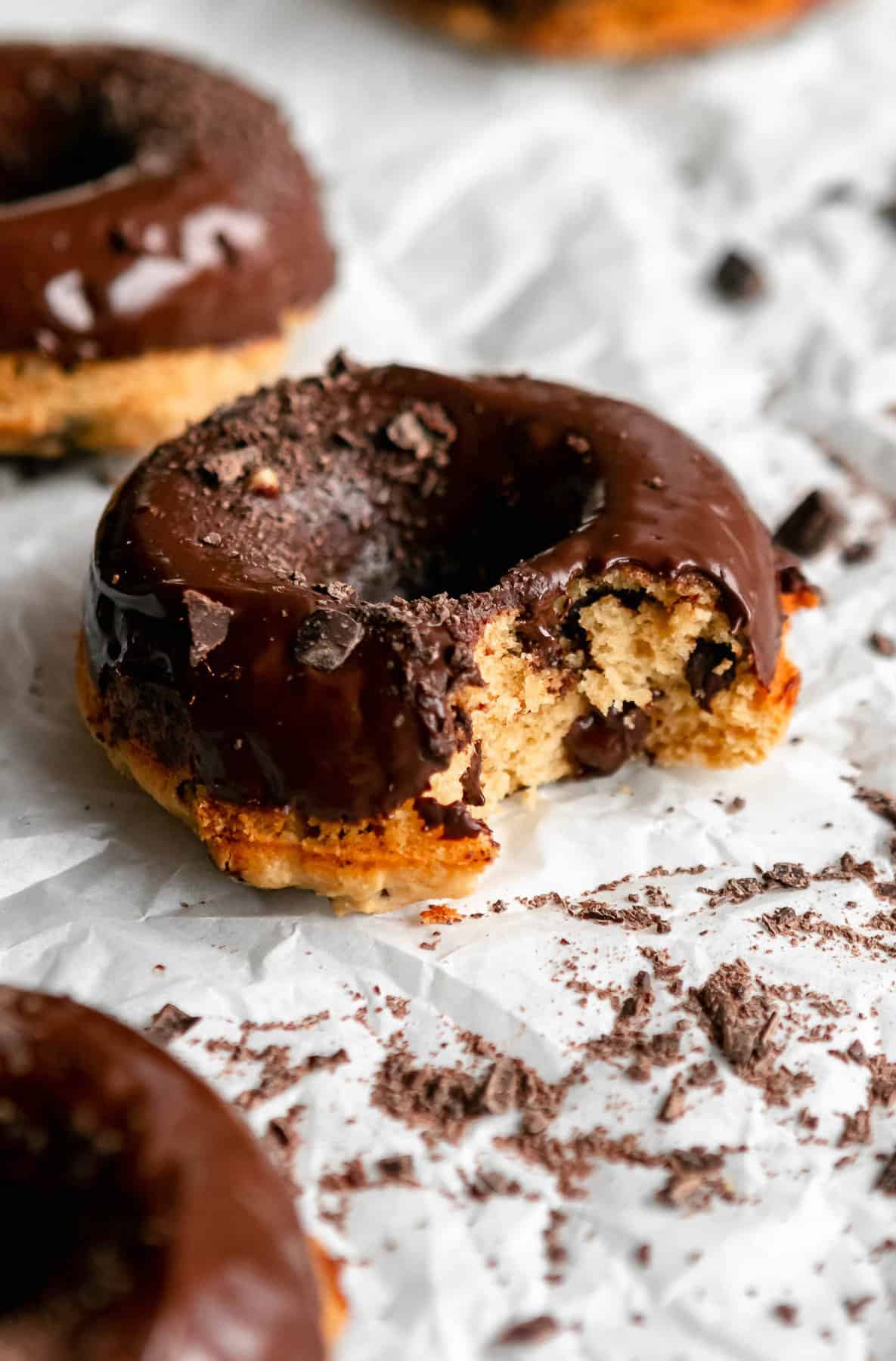protein chocolate chip donuts with chocolate glaze on parchment paper