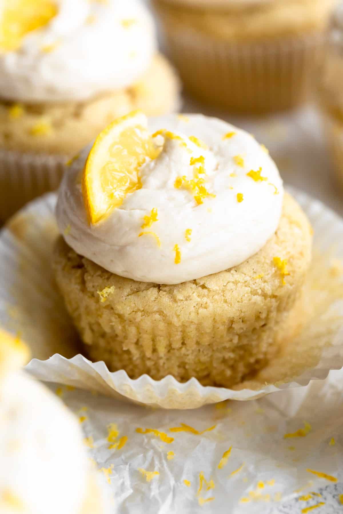 Vegan cupcakes arranged on a white backdrop with lemon wedges on top. 