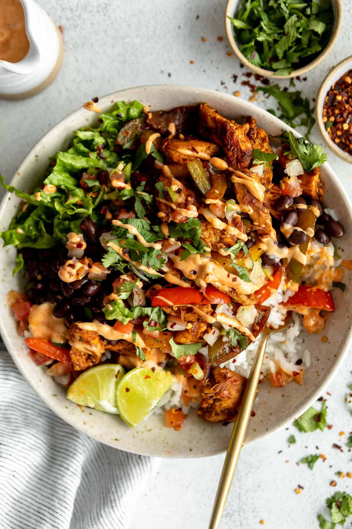 chicken fajita bowl with lettuce, black beans, peppers and lime